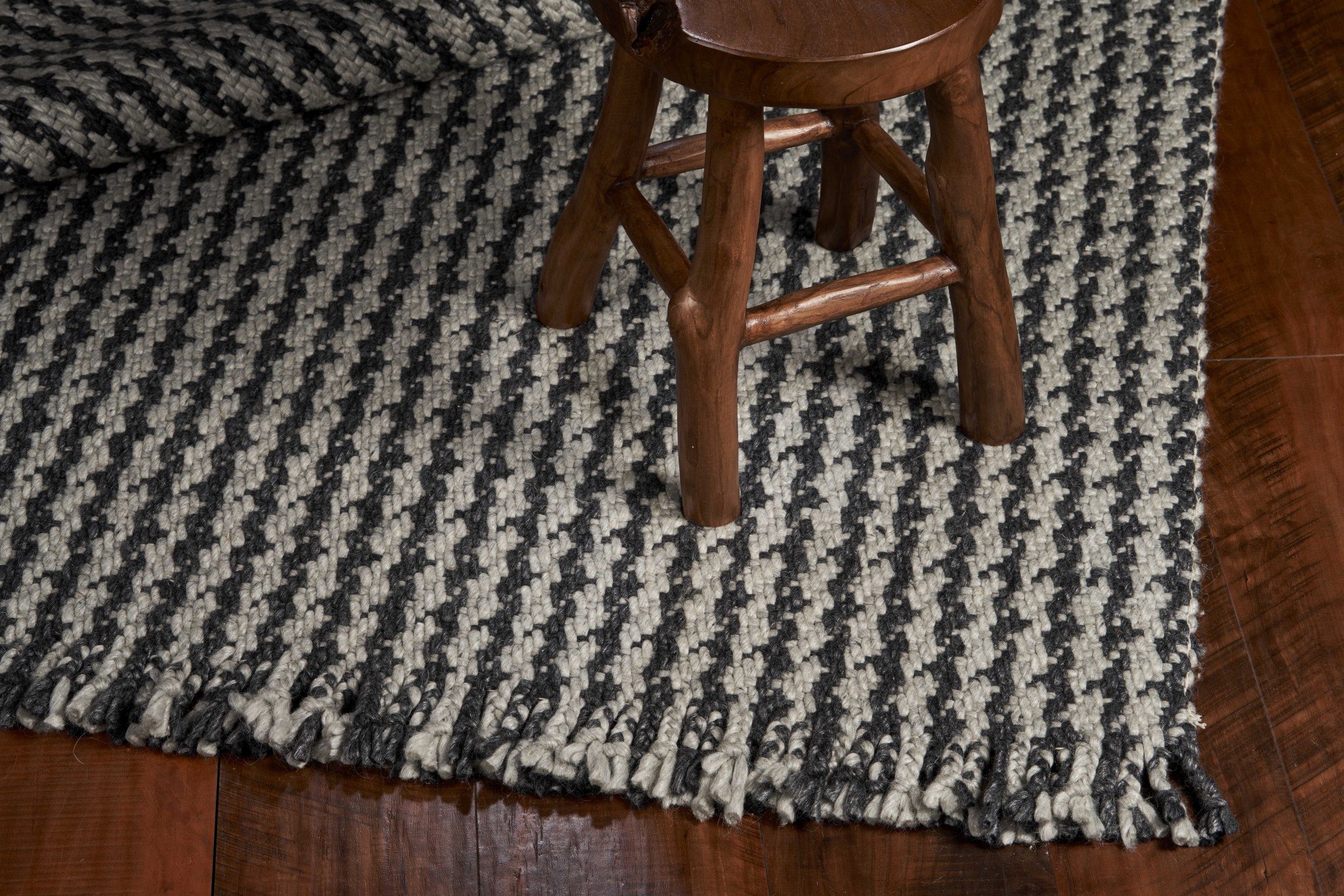 A beautifully crafted 8x10 grey hand woven houndstooth indoor area rug featuring a modern design and braided fringe, perfect for enhancing home decor.