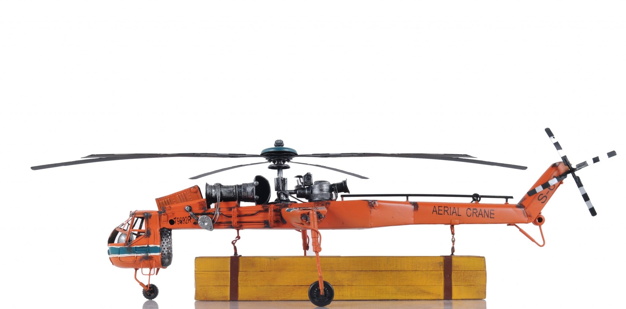 Aerial Crane Lifting Helicopter LED Sculpture showcasing intricate details and vibrant orange color, suspended with cargo and illuminated by LED lights.