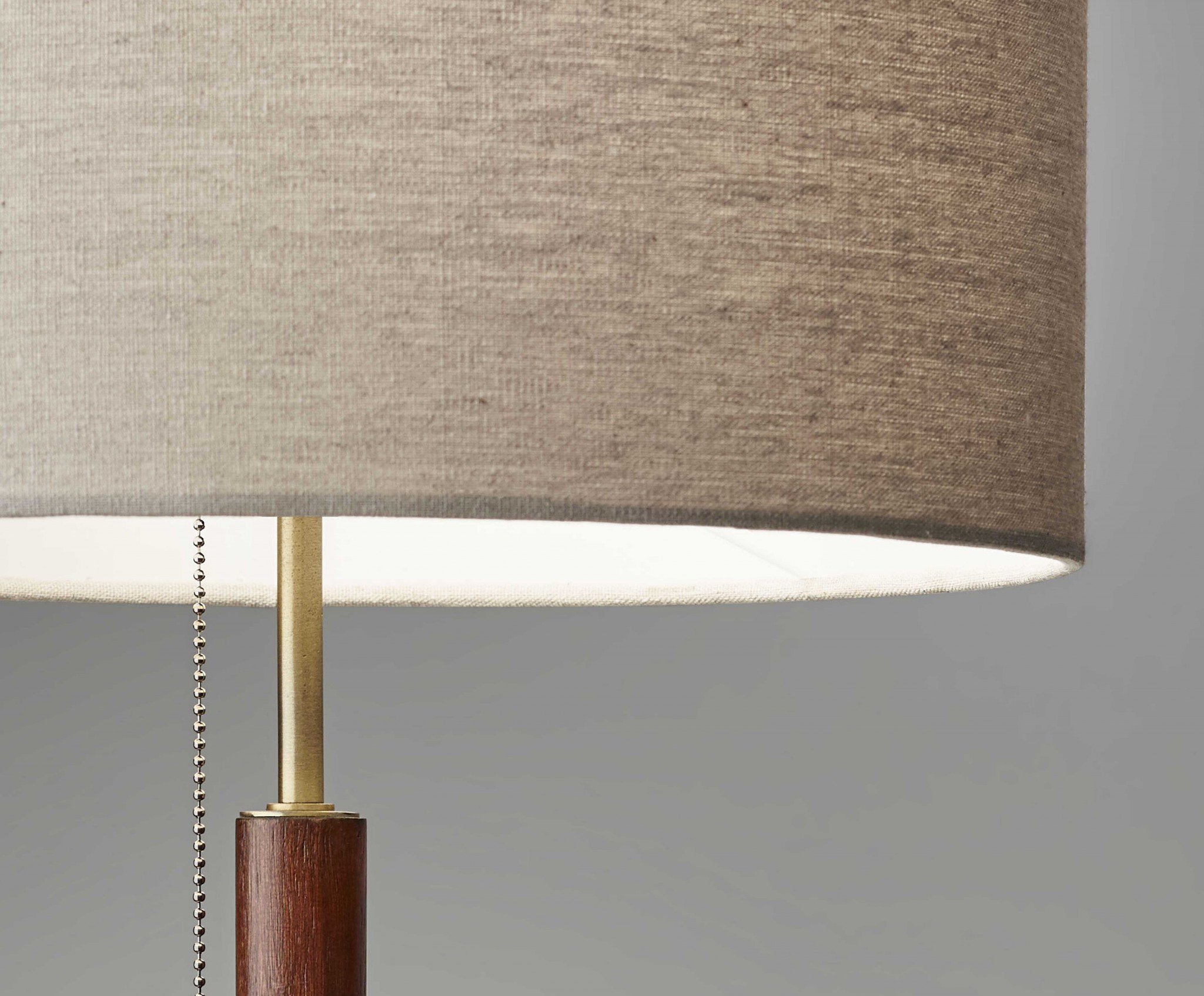 Antique brass metal and walnut wood table lamp with a natural linen shade and brass pull chain switch, perfect for mid-century modern decor.