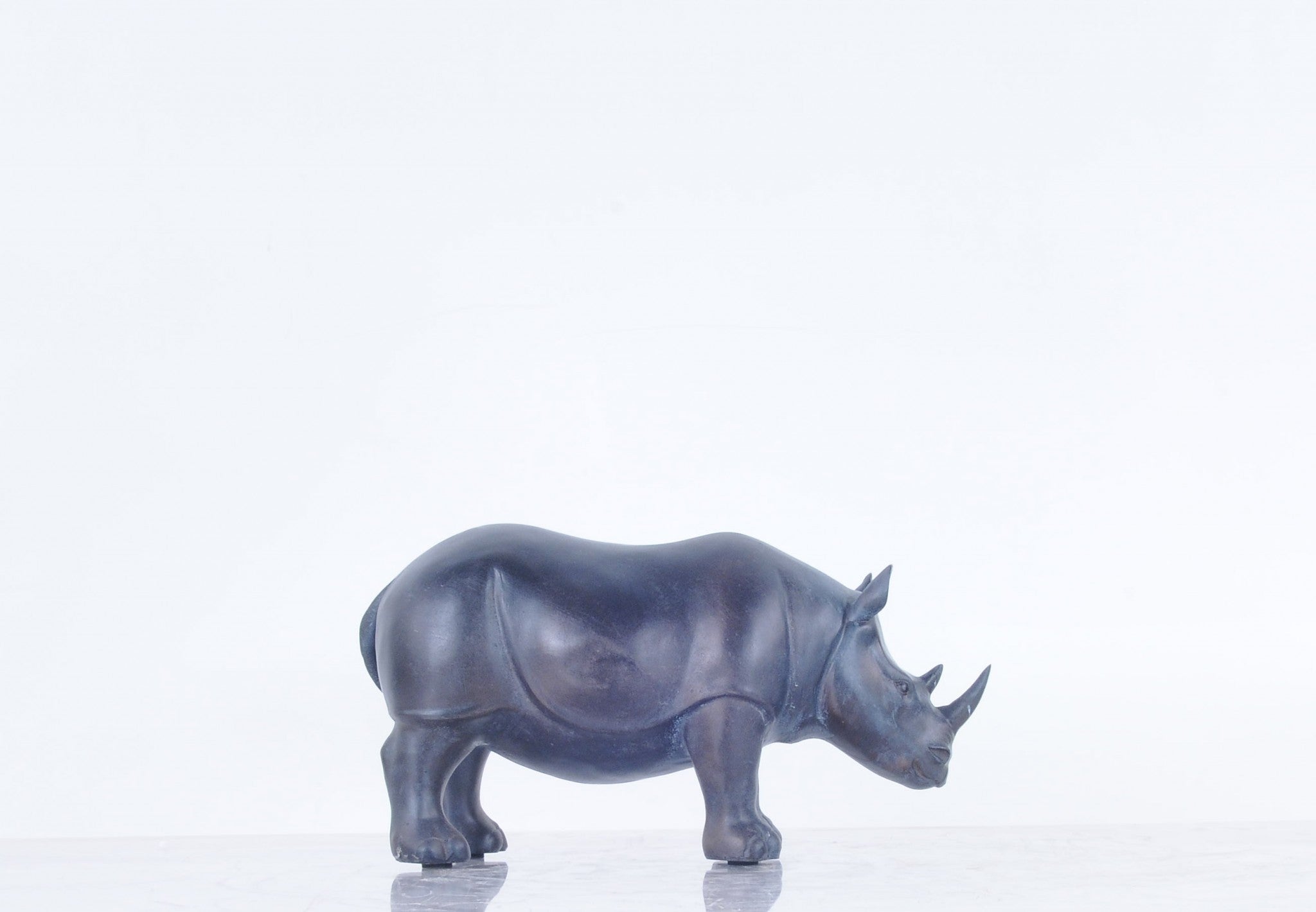 A stunning burnished bronze and black rhinoceros statue, showcasing intricate details and a powerful stance, perfect for home or office decor.