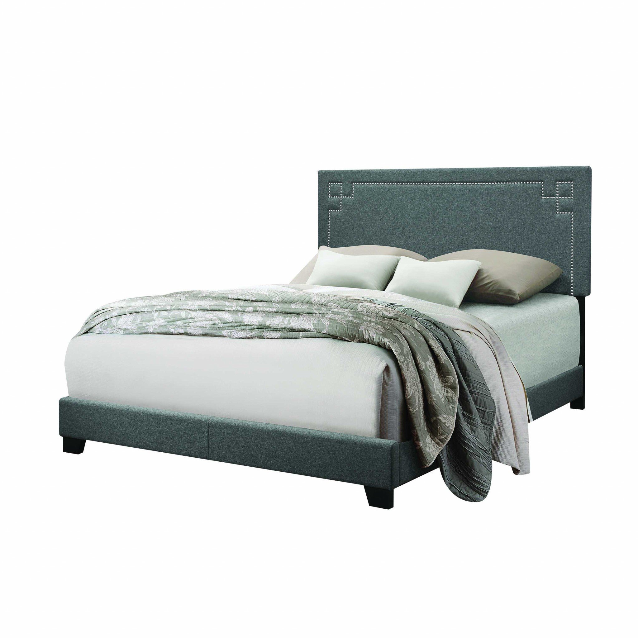 Contemporary gray upholstered king size bed with padded headboard and chrome nailhead trim, showcasing a modern design.