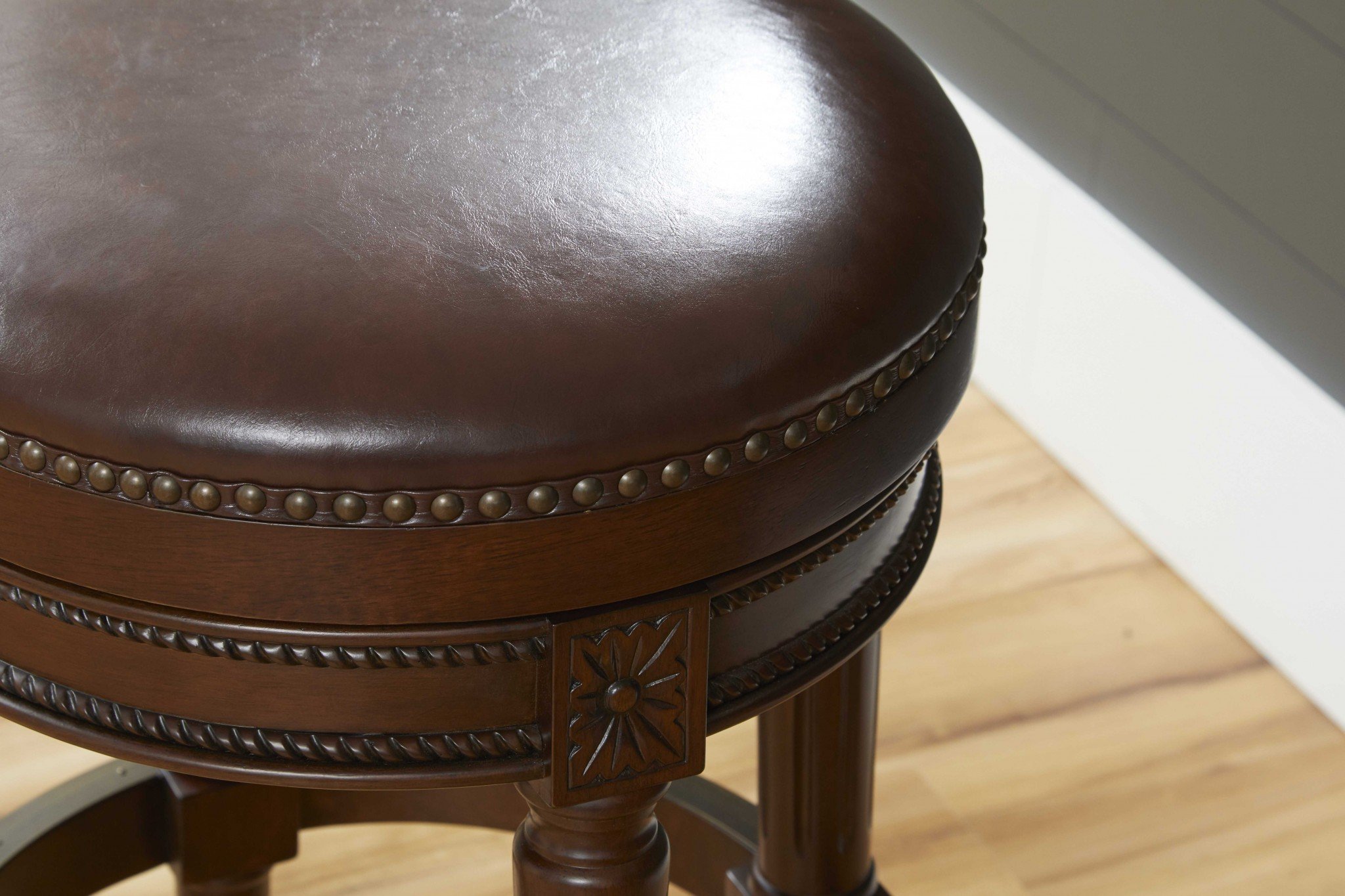 Distressed walnut finished bar height round stool with a sleek design and swivel seat, perfect for modern and rustic interiors.