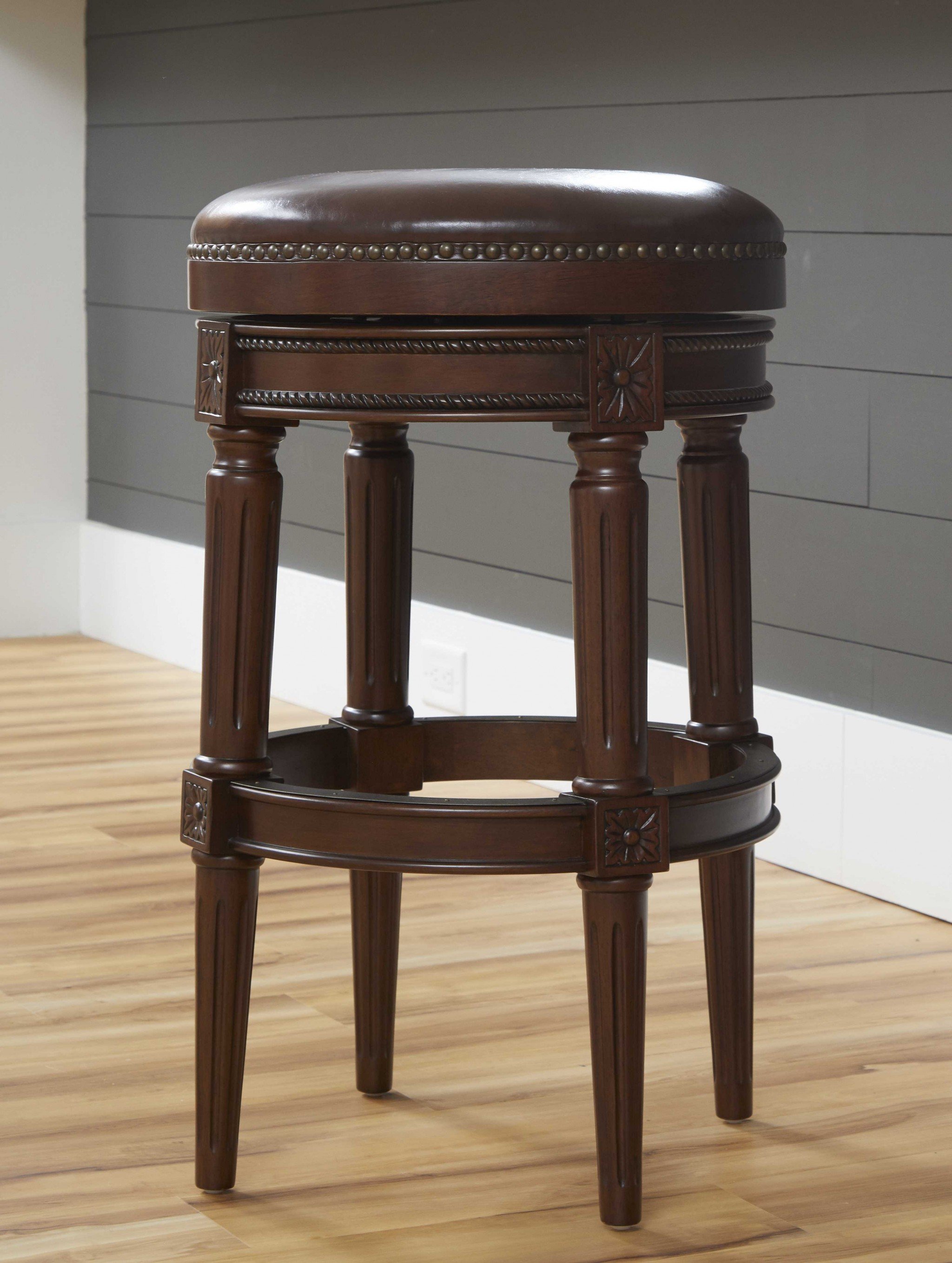 Distressed walnut finished bar height round stool with a sleek design and swivel seat, perfect for modern and rustic interiors.