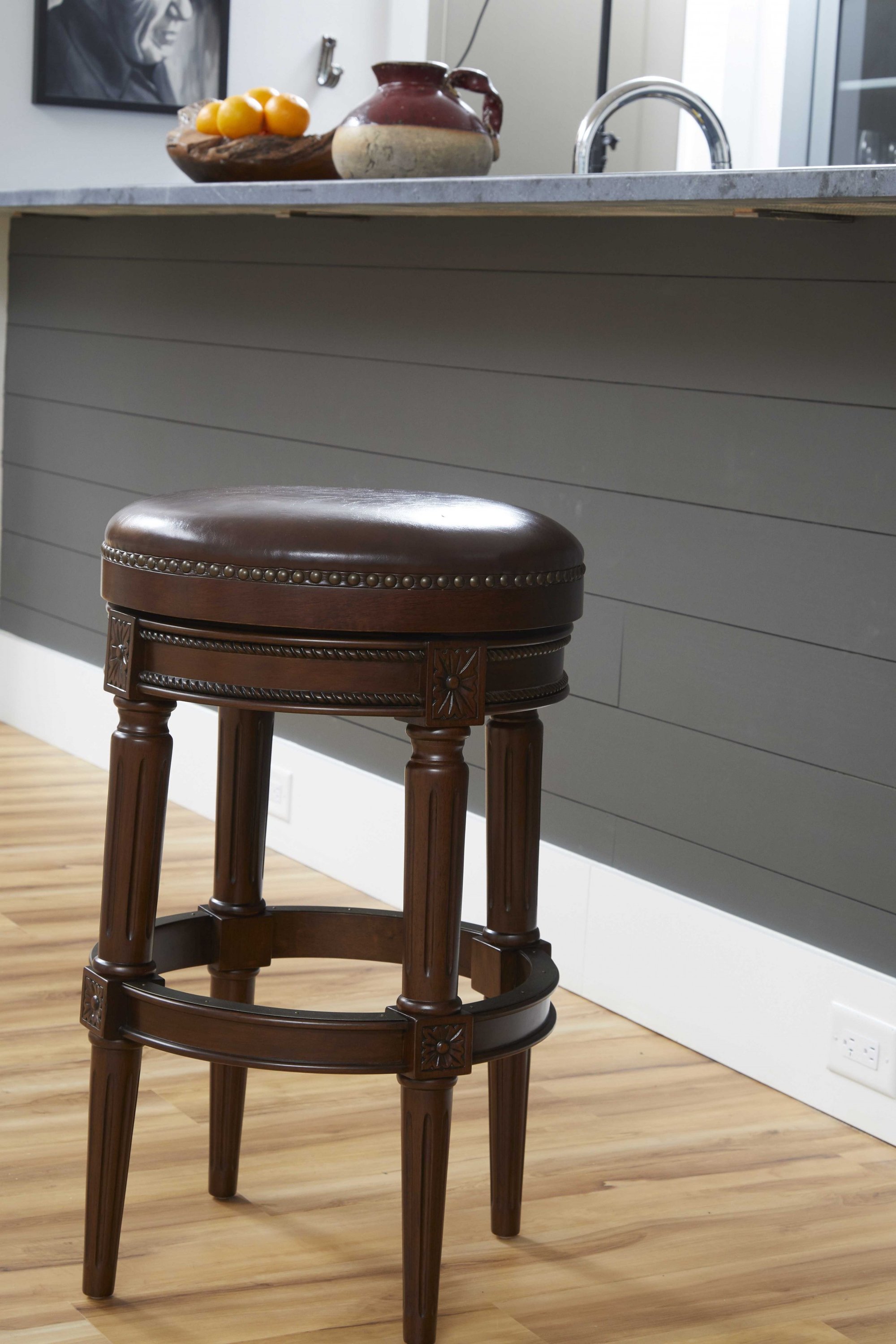 Distressed walnut finished bar height round stool with a sleek design and swivel seat, perfect for modern and rustic interiors.