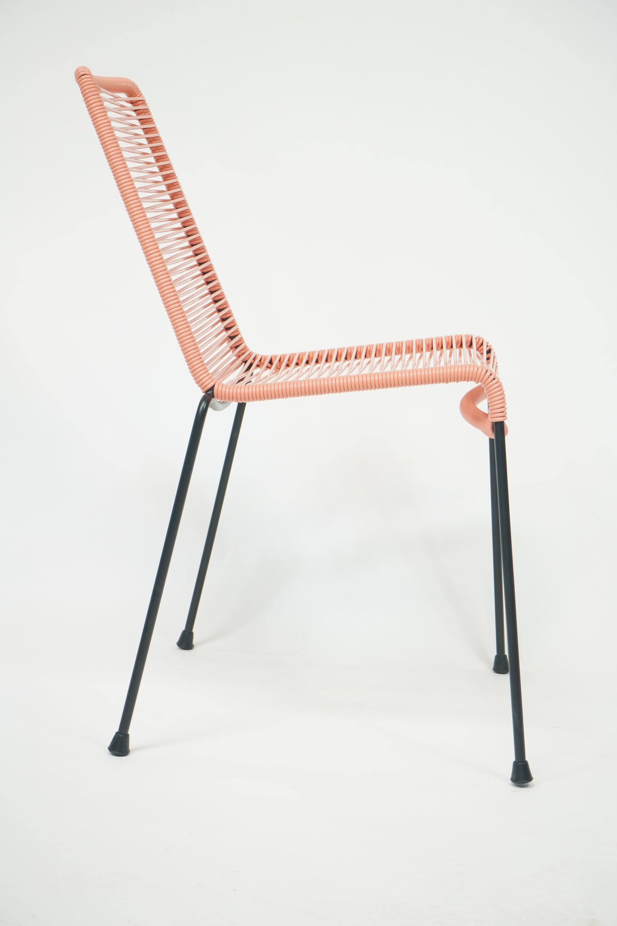 El Durazno Chair in peach and black, showcasing its stylish design and inviting curves.