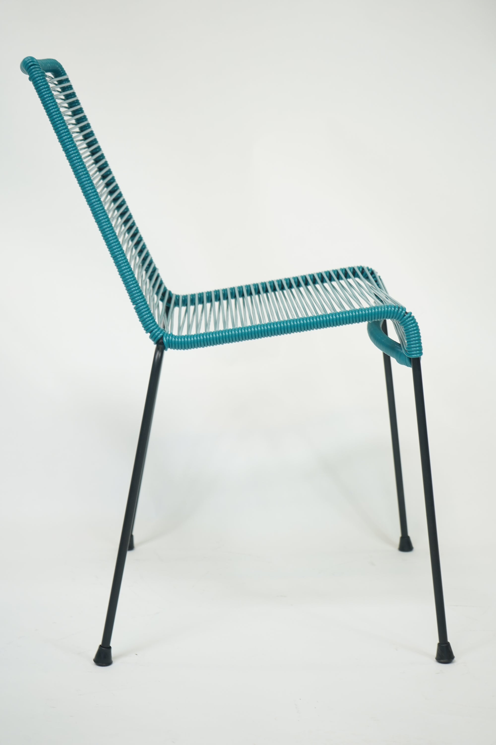 La Turquesa Chair in vibrant turquoise and black, showcasing its contemporary design and inviting curves.