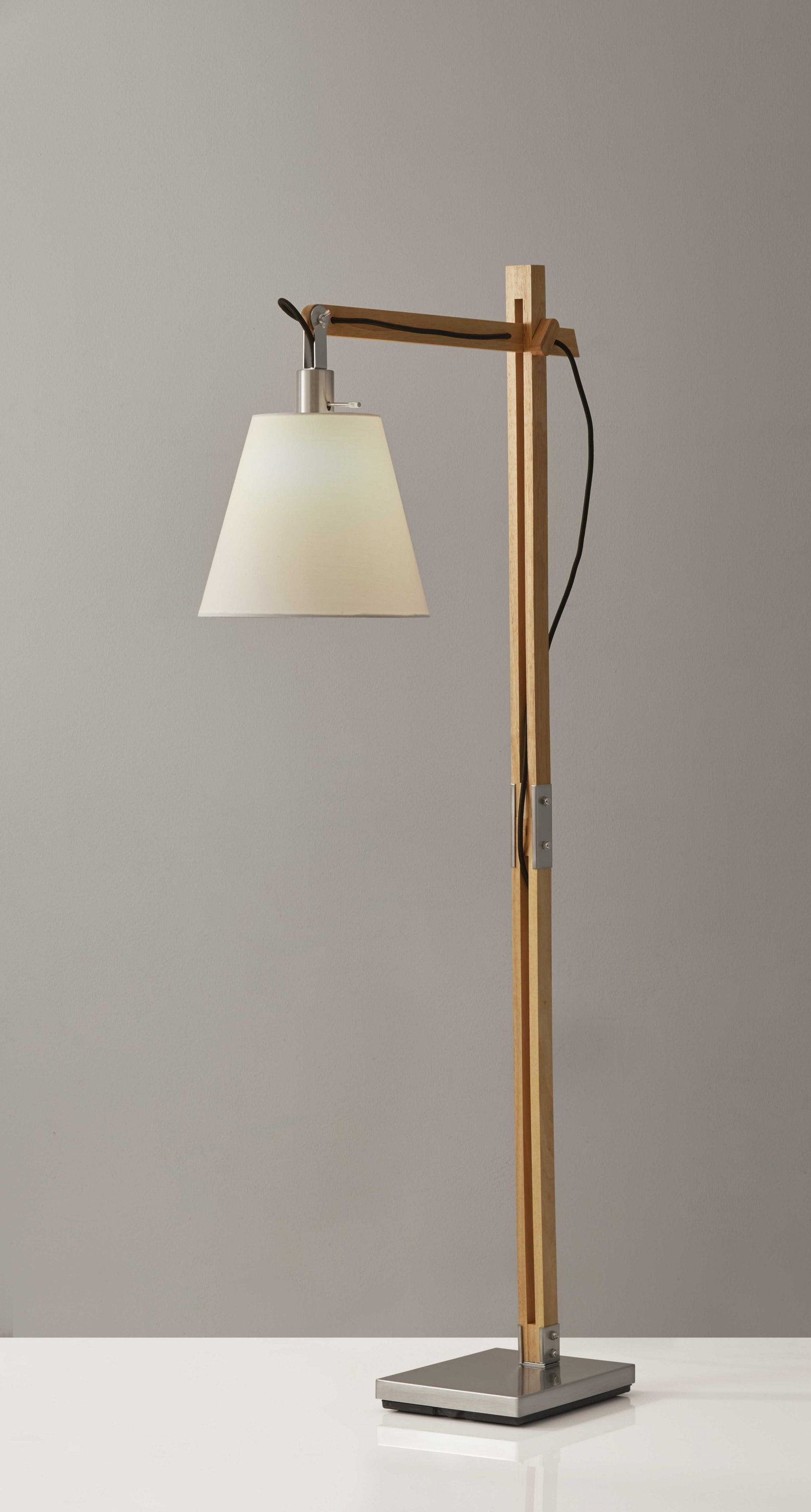 Natural wood floor lamp with adjustable hinged arm and off-white fabric shade, featuring a satin steel base.