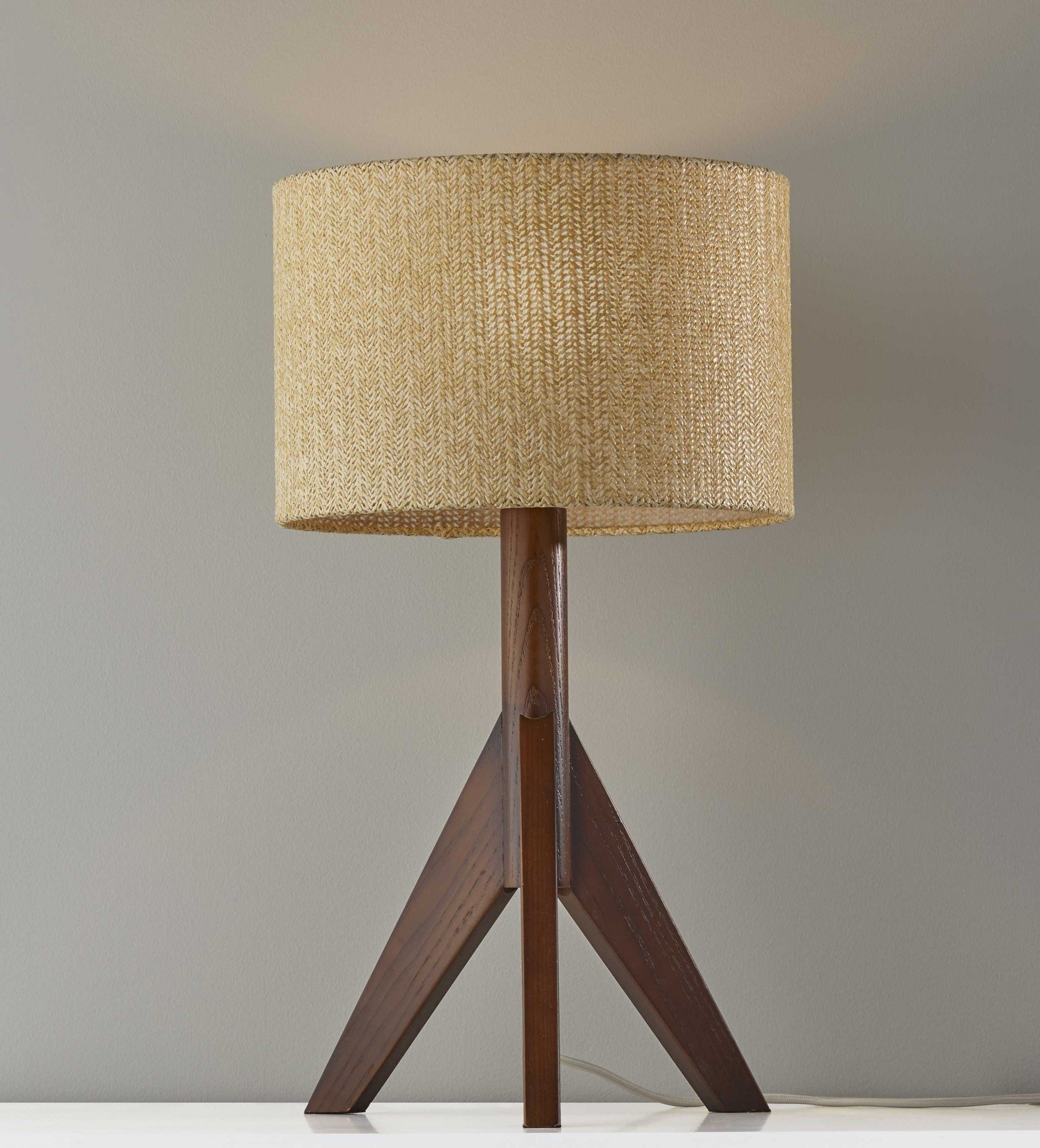 Natural wood tripod base table lamp with grey felt tapered drum shade, featuring a black and white fabric-covered cord.