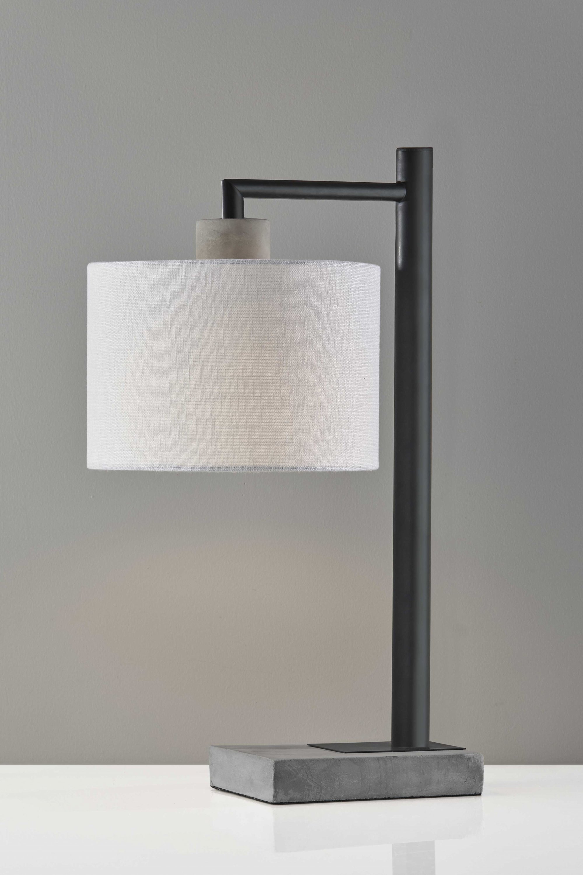 Petite black metal table lamp with grey cement accents and white textured fabric shade, showcasing a modern industrial design.