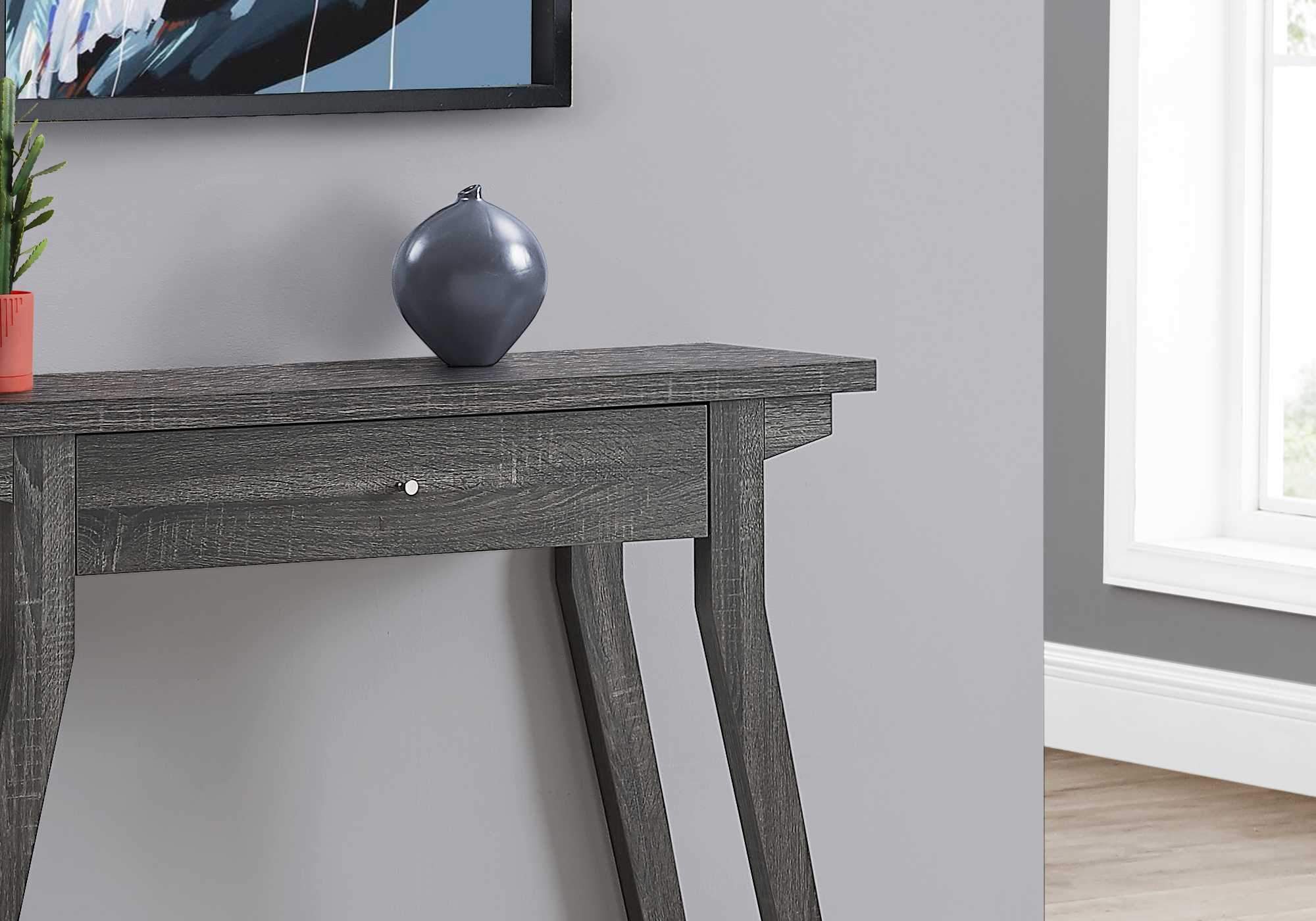 Rectangular grey accent table with a storage drawer and silver knob, featuring a reclaimed wood-look finish and angled legs.