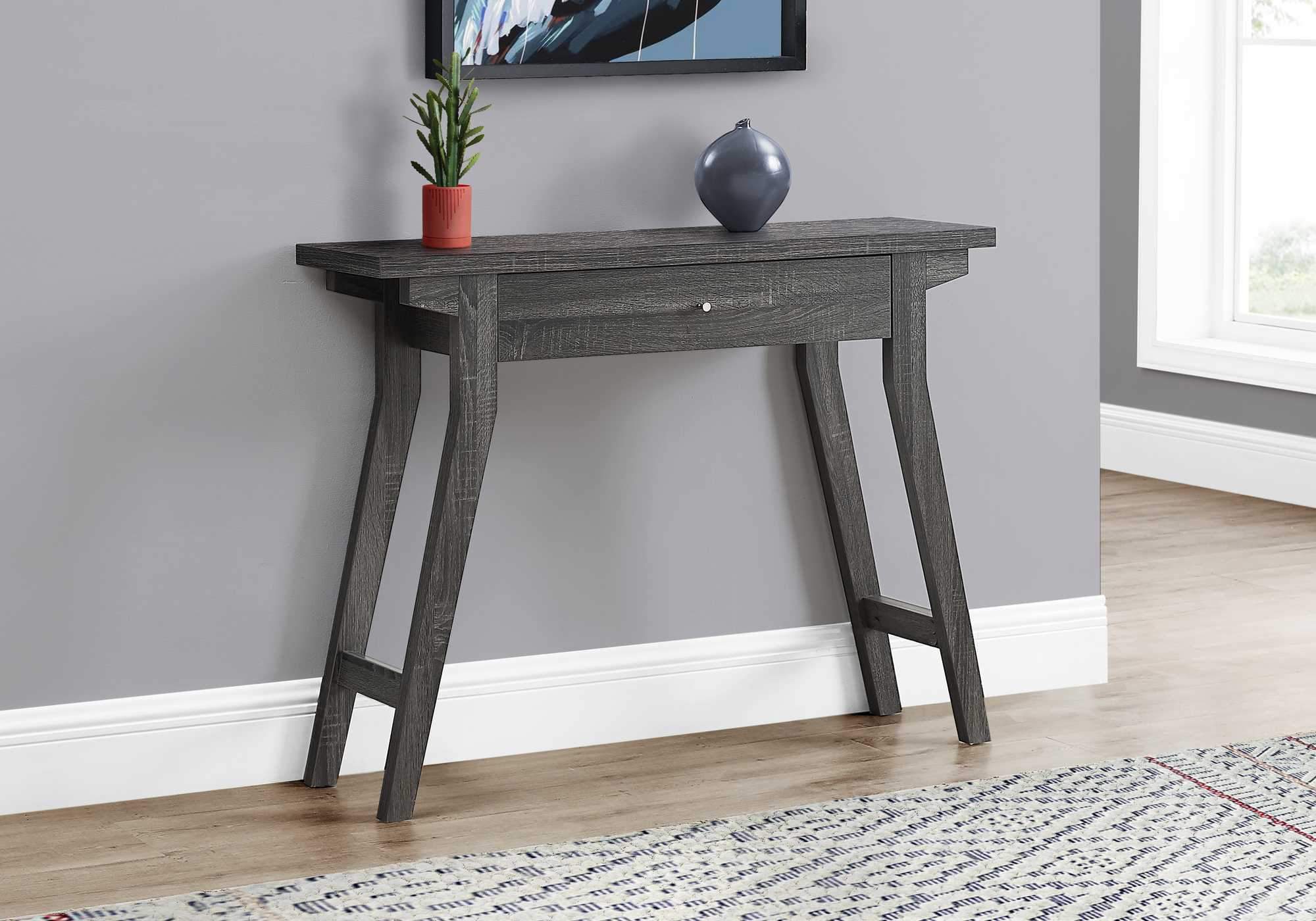 Rectangular grey accent table with a storage drawer and silver knob, featuring a reclaimed wood-look finish and angled legs.