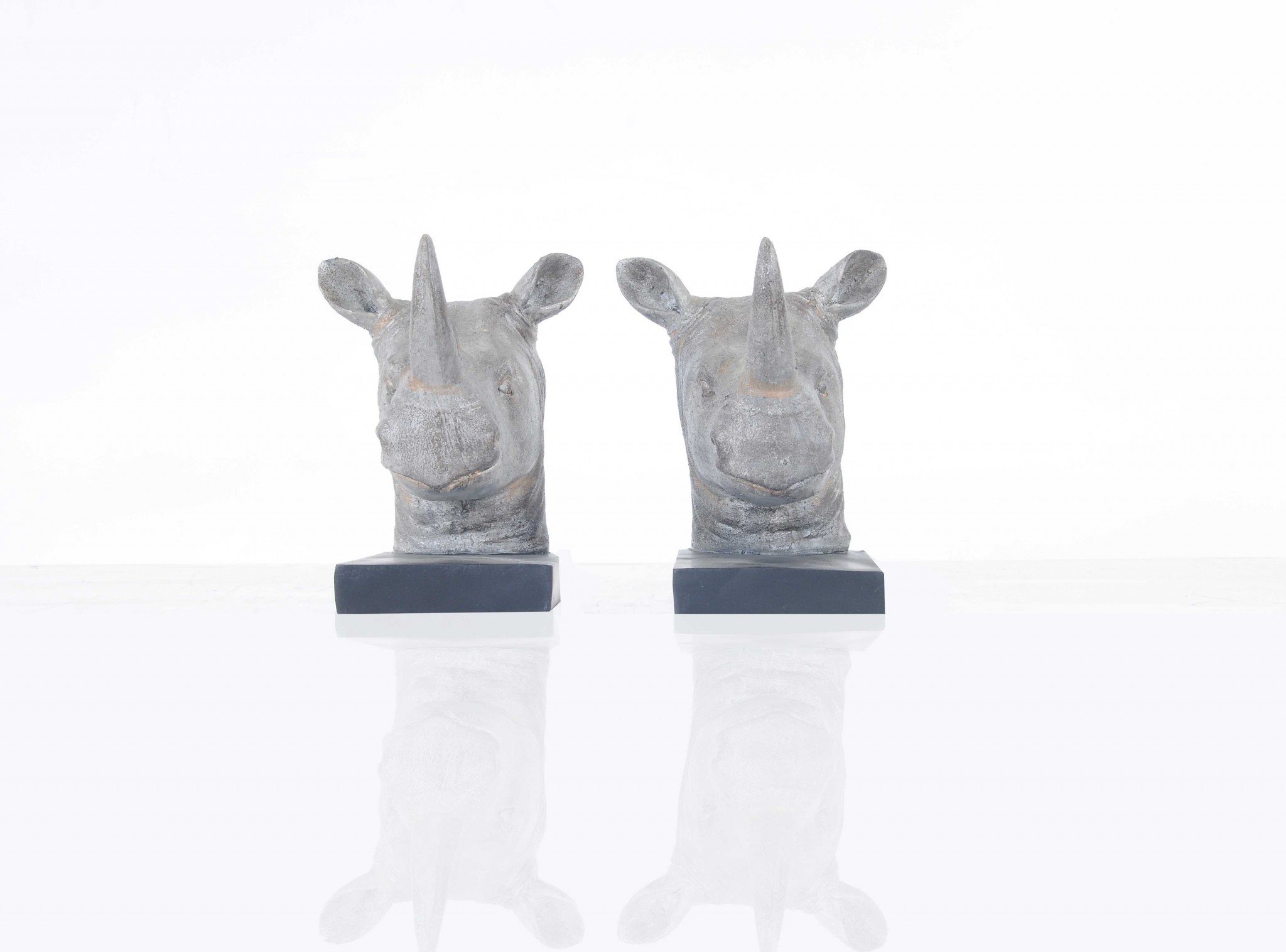 A set of two resin bookends featuring intricately designed rhino heads in dark grey with bronze accents, perfect for holding books upright.