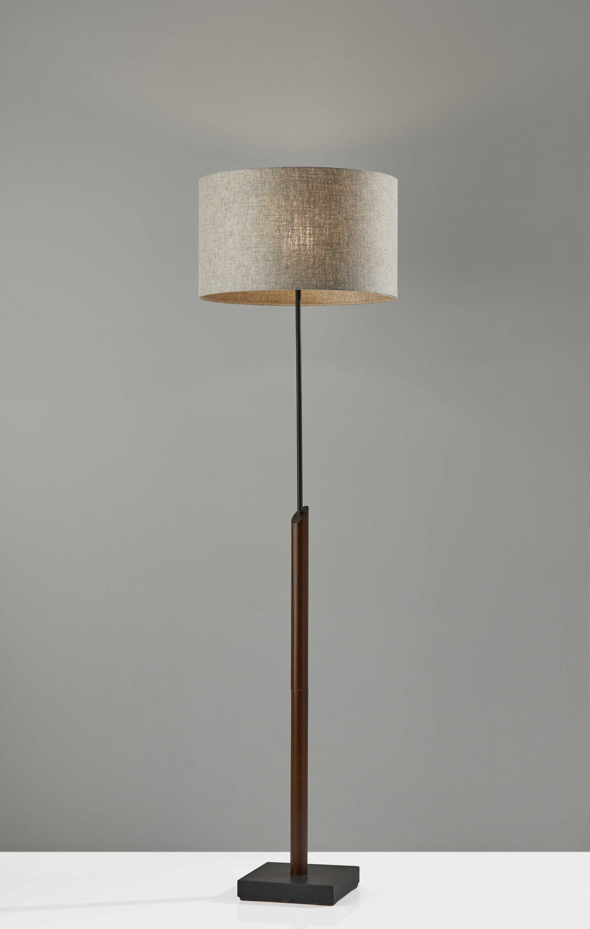 Sculptural wood floor lamp with black metal accents and natural fabric shade, showcasing a modern design and compact base.