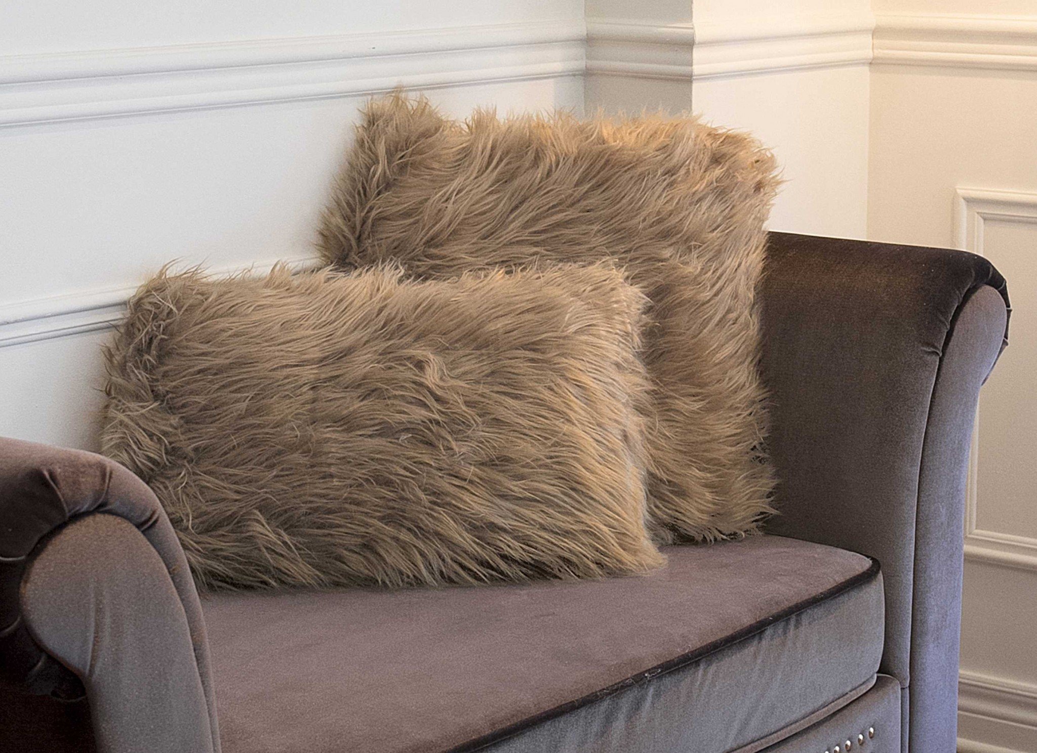 Two luxurious tan faux fur pillows with plush texture, perfect for home decor.