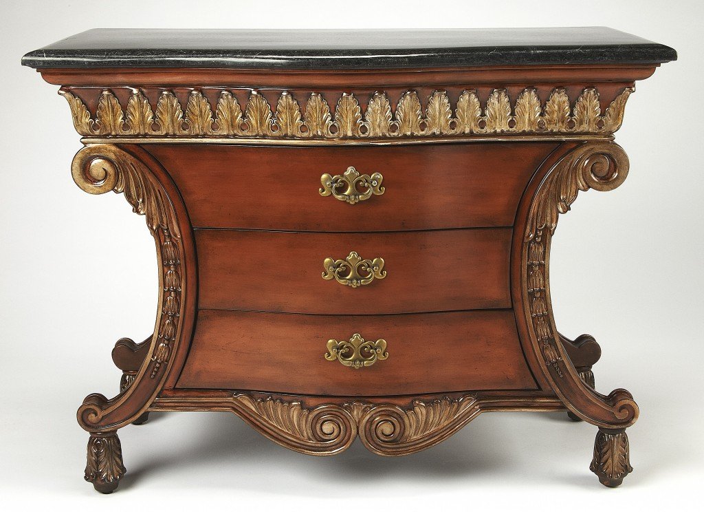 Traditional carved chest featuring a black fossil stone top and antique brass hardware, showcasing intricate woodwork and elegant design.