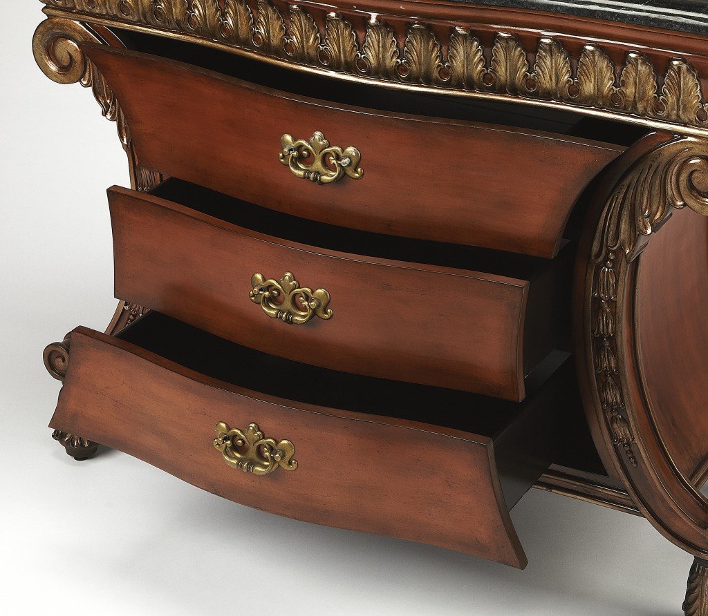 Traditional carved chest featuring a black fossil stone top and antique brass hardware, showcasing intricate woodwork and elegant design.