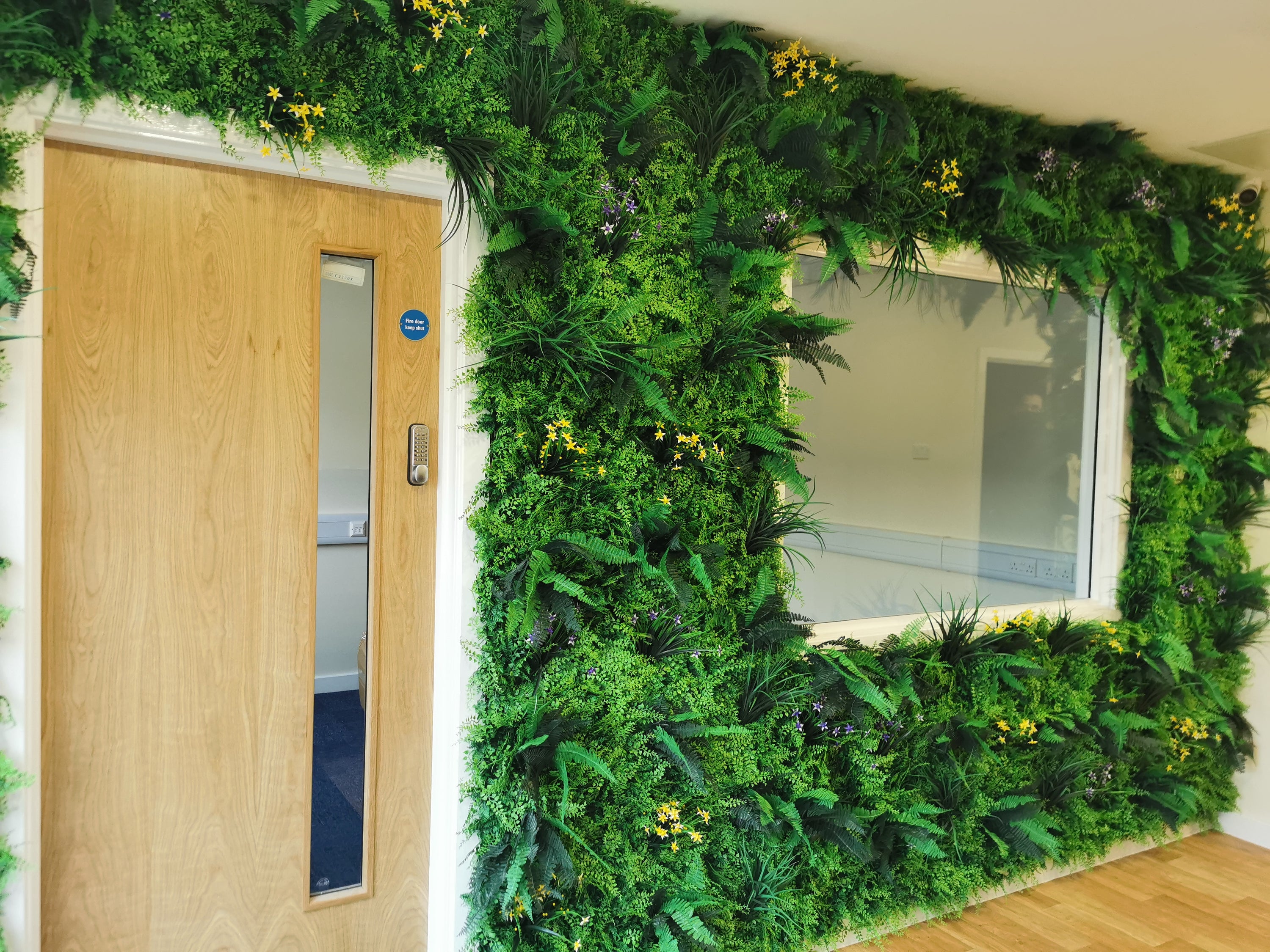 Flame Resistant Artificial Green Wall Hedge Panel measuring 100 x 100 cm, featuring a mix of lush leaves, grass, and fern for a dense, luxurious appearance.