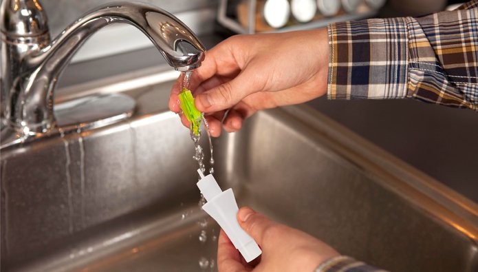 Person rinsing small object in sink.