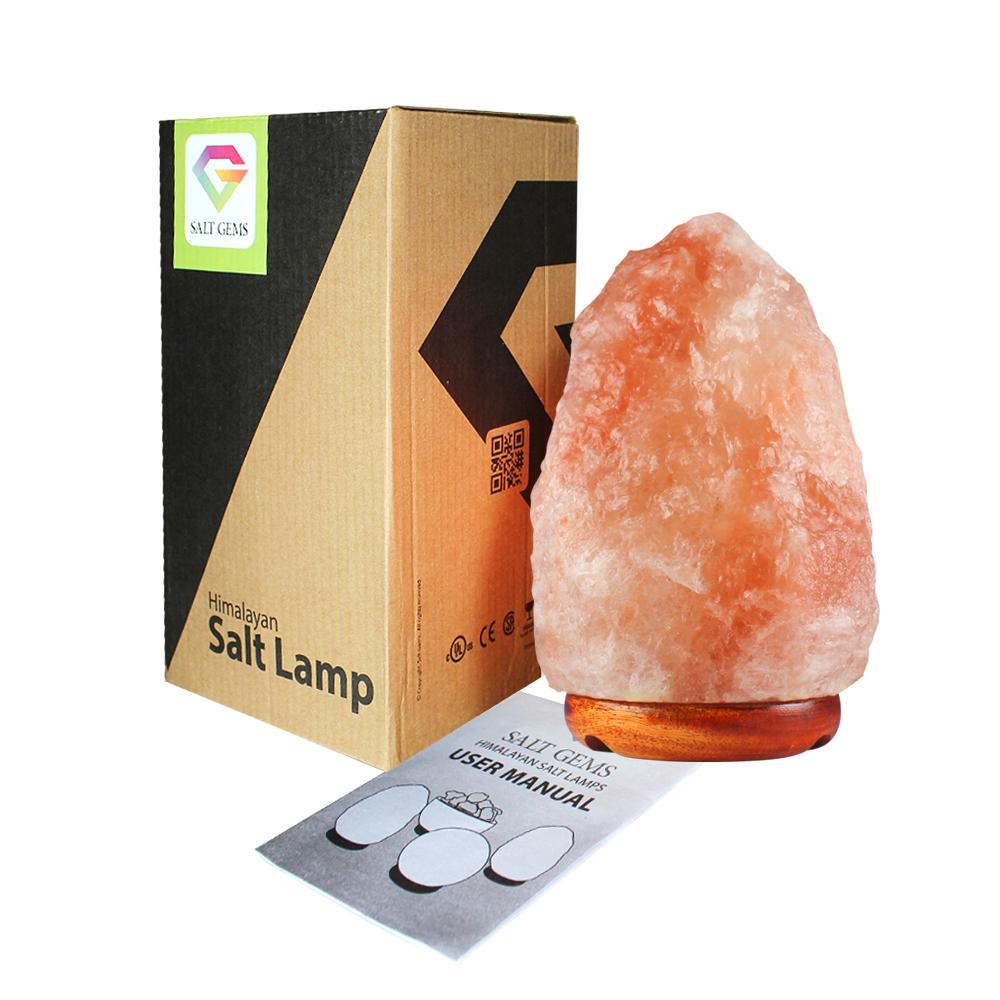 A pair of hand-carved Himalayan salt lamps with unique shapes, emitting a warm amber glow, placed on a wooden surface.