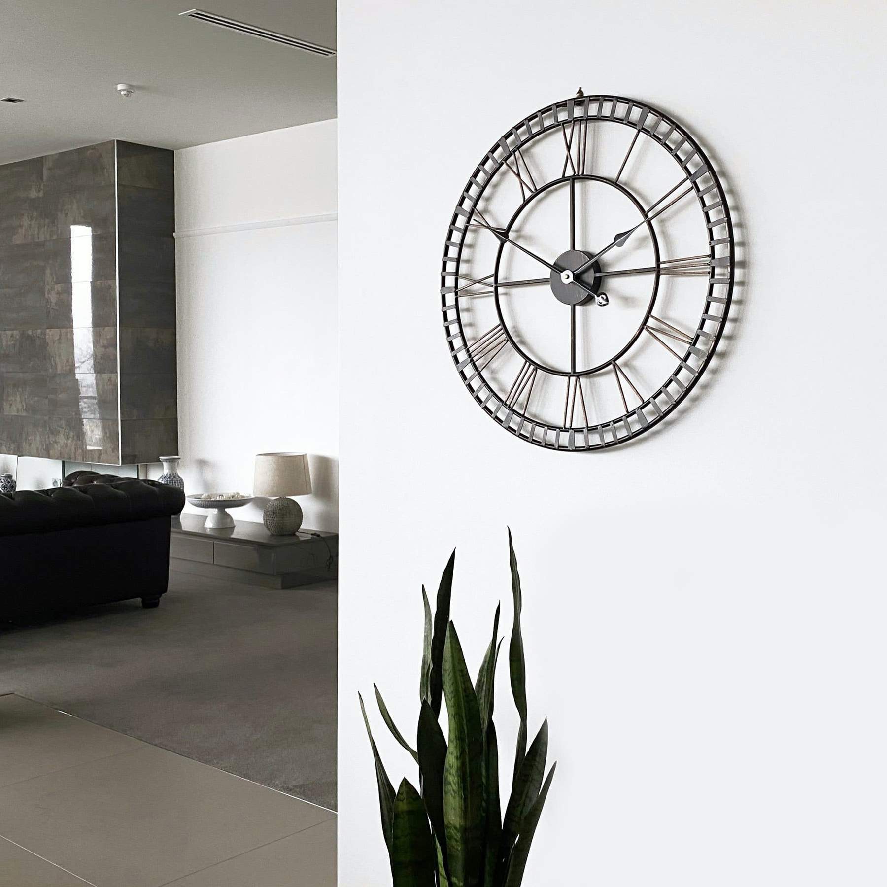 A 24-inch round oversized black metal wall clock featuring Roman numerals and a sleek silver frame, perfect for home décor.