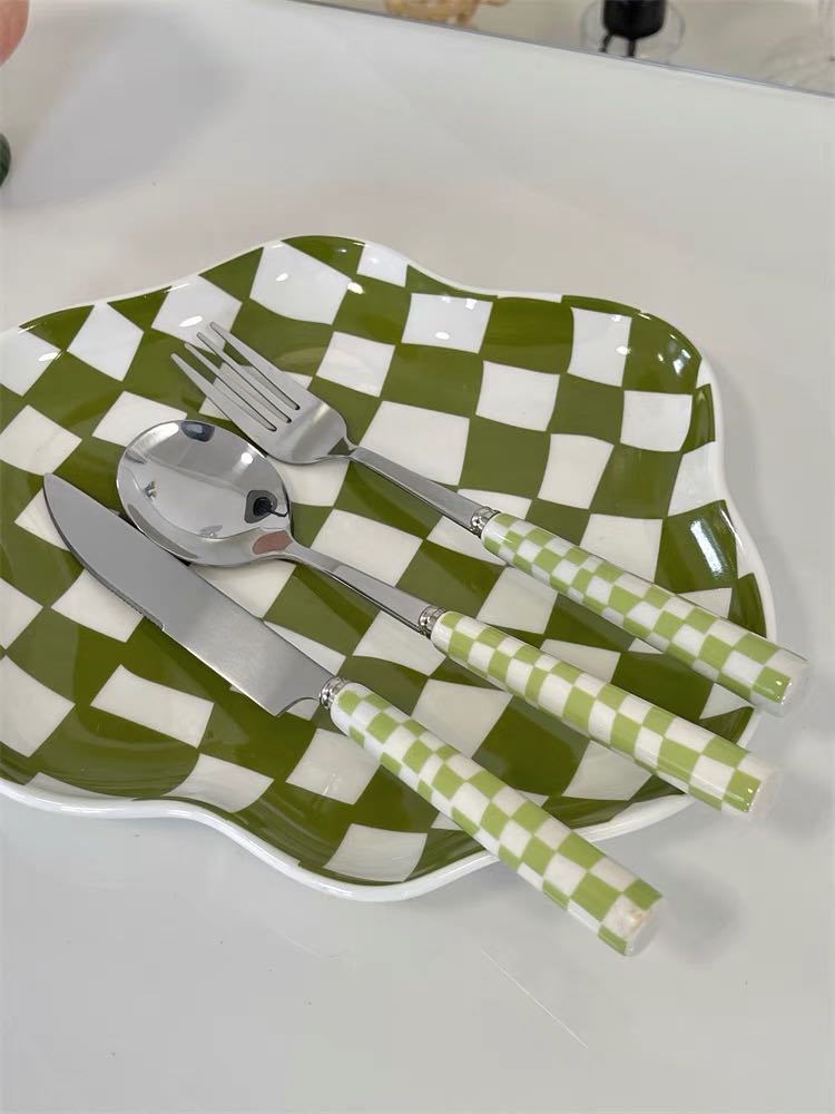 A vibrant 6-pack modern checkered flatware set featuring stainless steel utensils with colorful ceramic handles in red, yellow, green, and black.