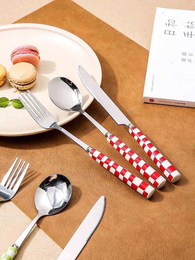 A vibrant 6-pack modern checkered flatware set featuring stainless steel utensils with colorful ceramic handles in red, yellow, green, and black.