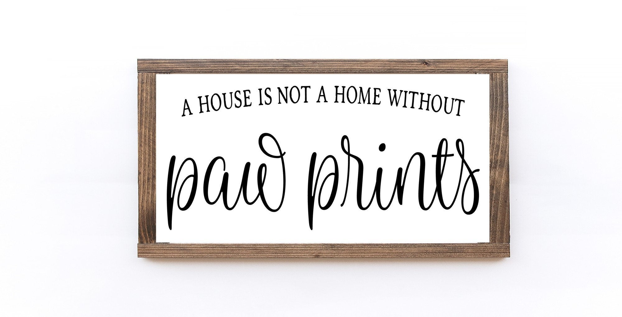 A rustic wood sign that reads 'A House Is Not A Home Without Paw Prints', featuring a matte white background and unique wood grain.