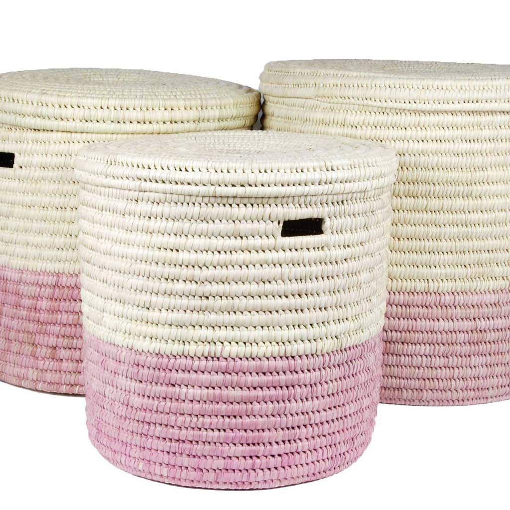 A vibrant African handcrafted laundry basket made from doum palm leaf, featuring a raspberry pink color block design, showcasing its lidded structure and unique craftsmanship.