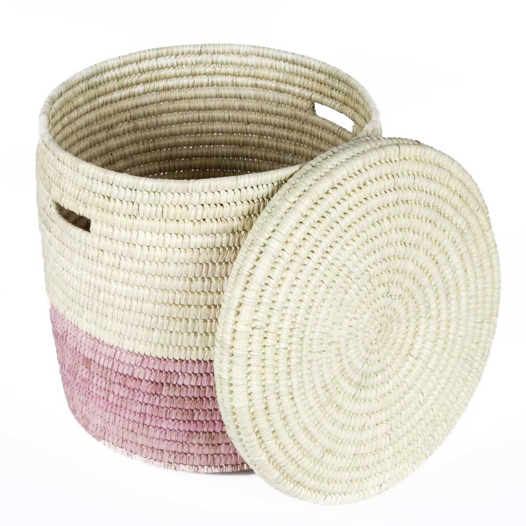 A vibrant African handcrafted laundry basket made from doum palm leaf, featuring a raspberry pink color block design, showcasing its lidded structure and unique craftsmanship.