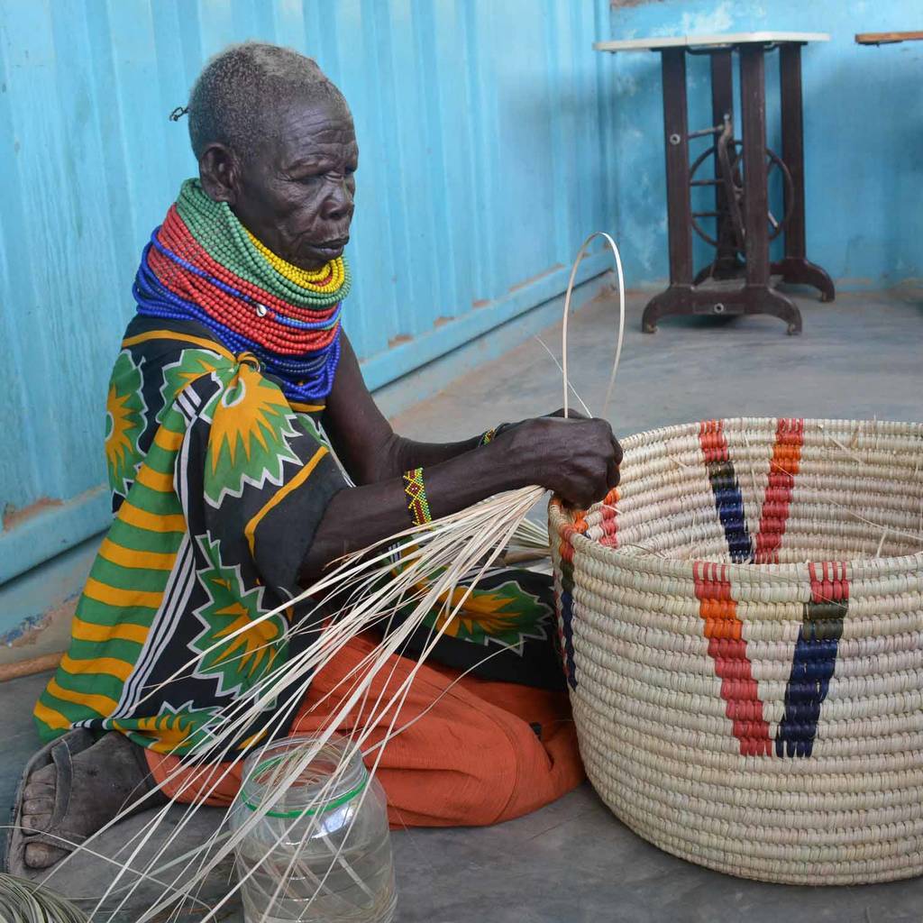 A vibrant African handcrafted laundry basket made from doum palm leaf, featuring a raspberry pink color block design, showcasing its lidded structure and unique craftsmanship.