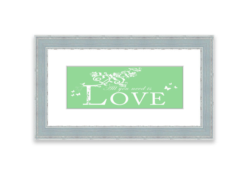 Framed print of 'All You Need Is Love' in green, showcasing vibrant colors and a heartfelt message, ready to hang.