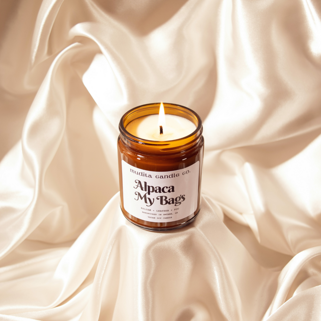 Alpaca My Bags Balsam Leather Soy Candle in amber glass jar with gold lid, showcasing its cozy and inviting scent.