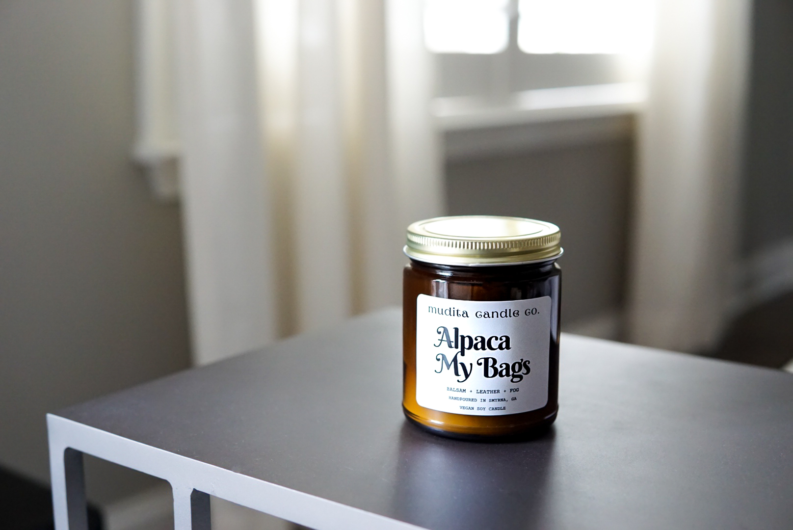 Alpaca My Bags Balsam Leather Soy Candle in amber glass jar with gold lid, showcasing its cozy and inviting scent.