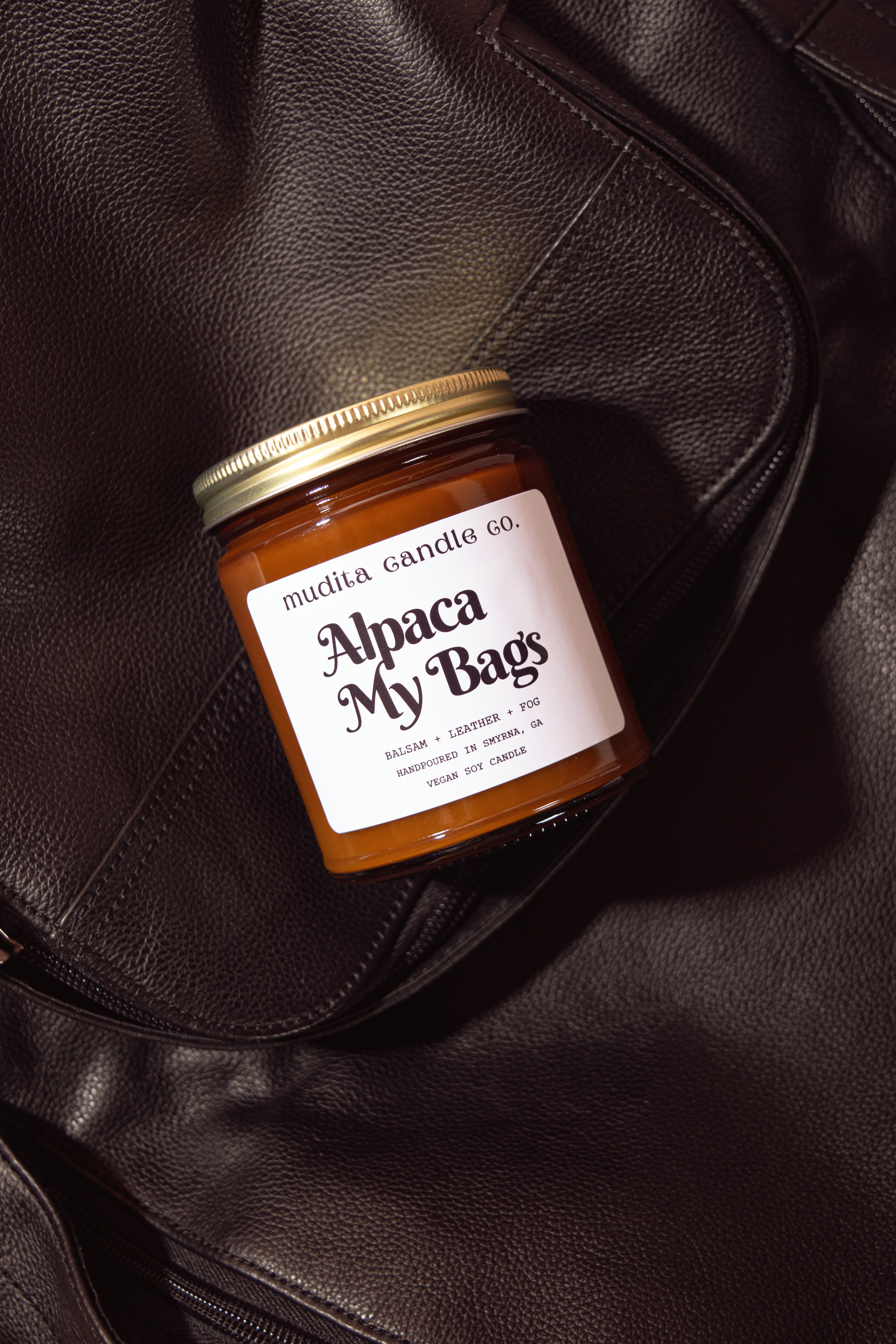 Alpaca My Bags Balsam Leather Soy Candle in amber glass jar with gold lid, showcasing its cozy and inviting scent.