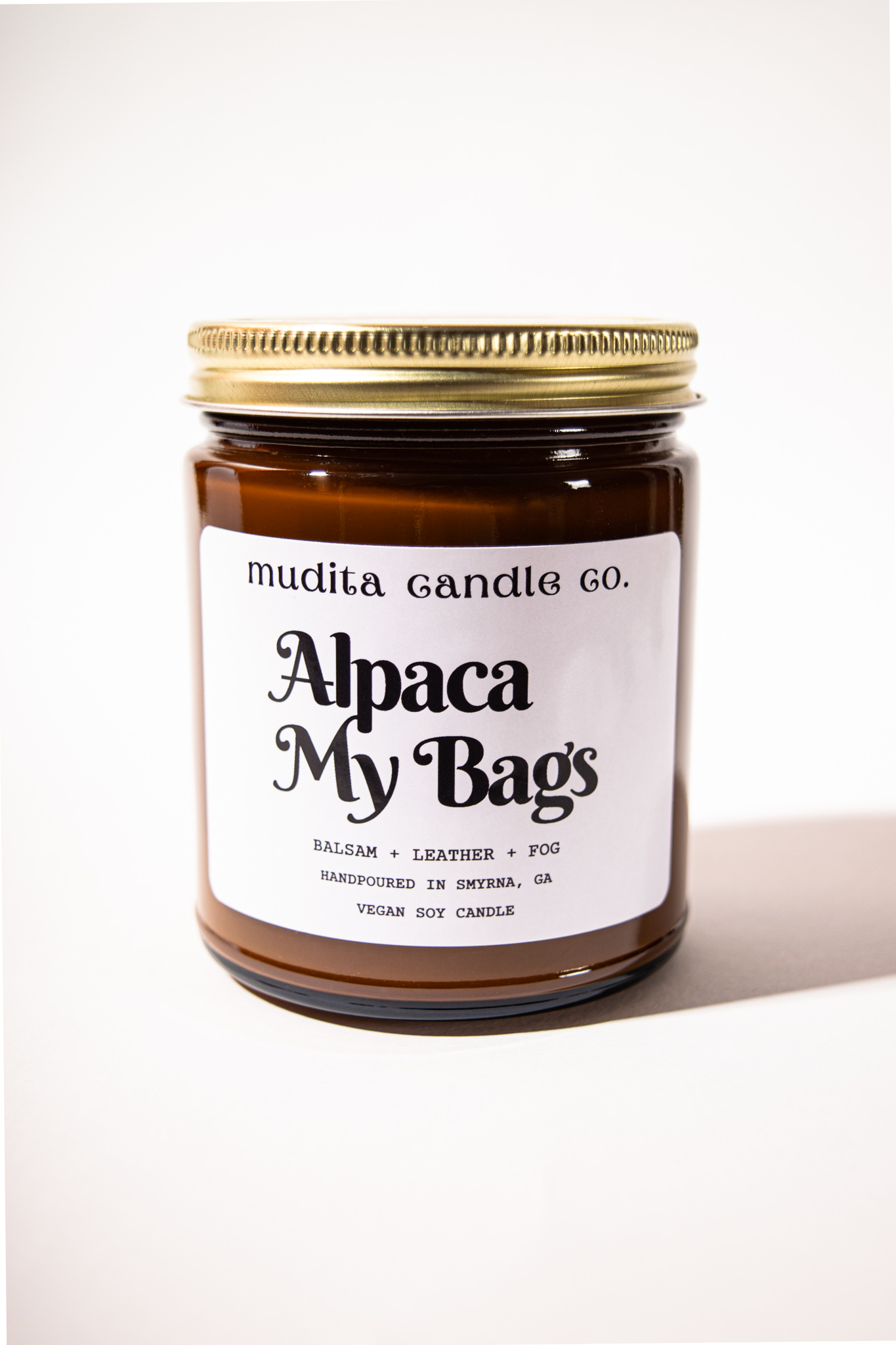 Alpaca My Bags Balsam Leather Soy Candle in amber glass jar with gold lid, showcasing its cozy and inviting scent.