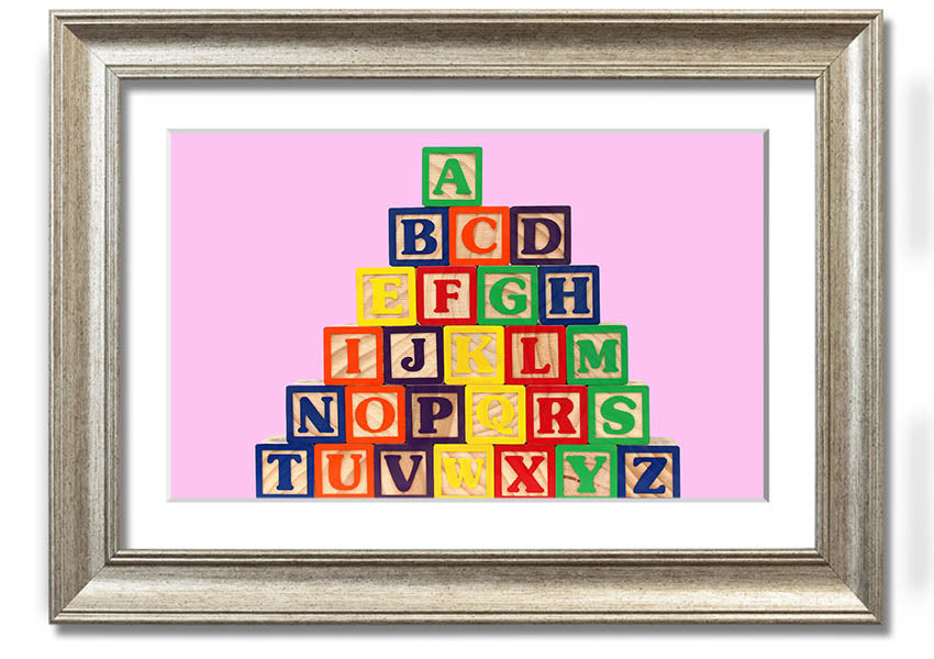 A charming pink framed print featuring colorful alphabet blocks, perfect for nursery decor.