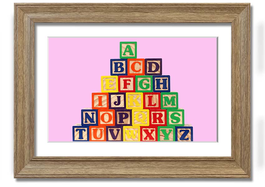 A charming pink framed print featuring colorful alphabet blocks, perfect for nursery decor.