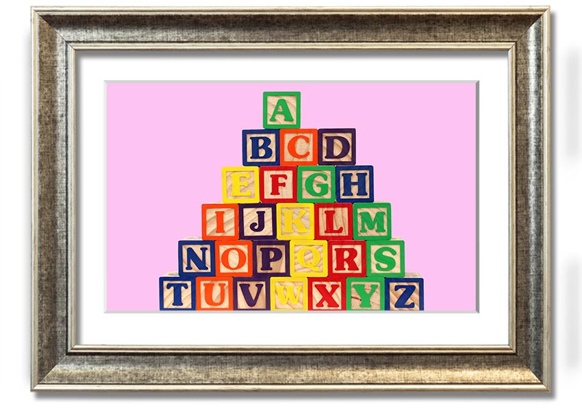 A charming pink framed print featuring colorful alphabet blocks, perfect for nursery decor.