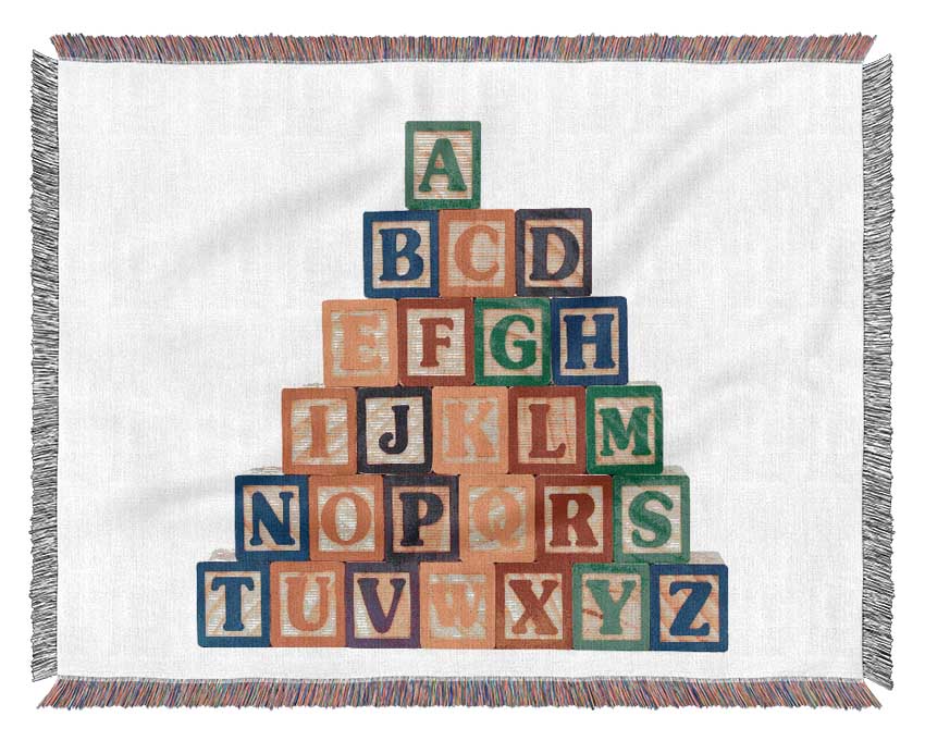 A soft pink blanket featuring alphabet blocks design, made from 100% cotton, draped elegantly on a couch.