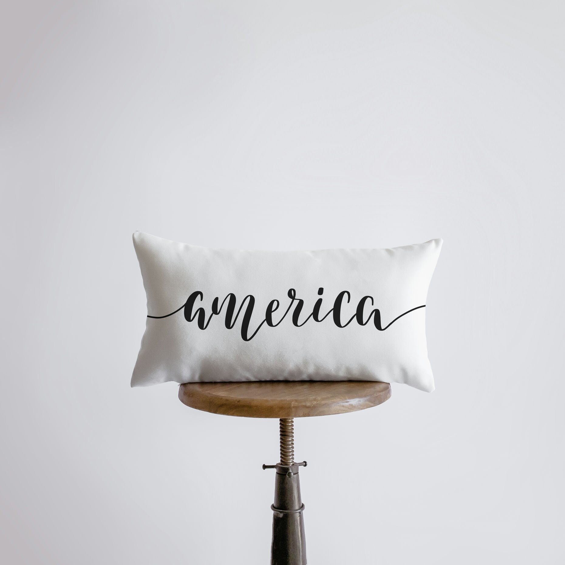 Hand-made America Pillow Cover featuring the word 'America' on the front, measuring 20x10 inches, made from a durable cotton/polyester blend.