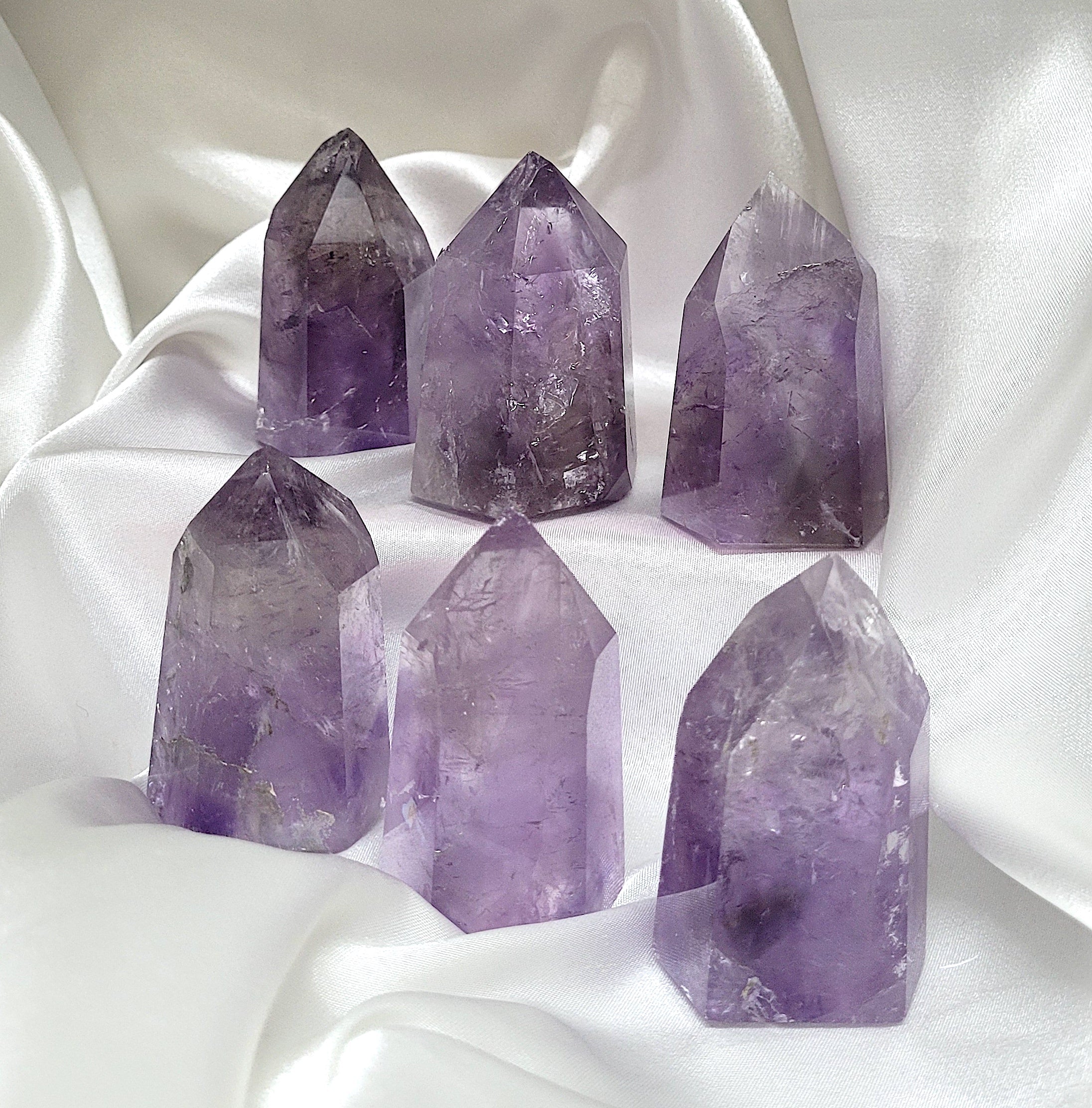 A hand-carved Amethyst Generator crystal with rainbow and smoky inclusions, showcasing its unique shape and calming energy.