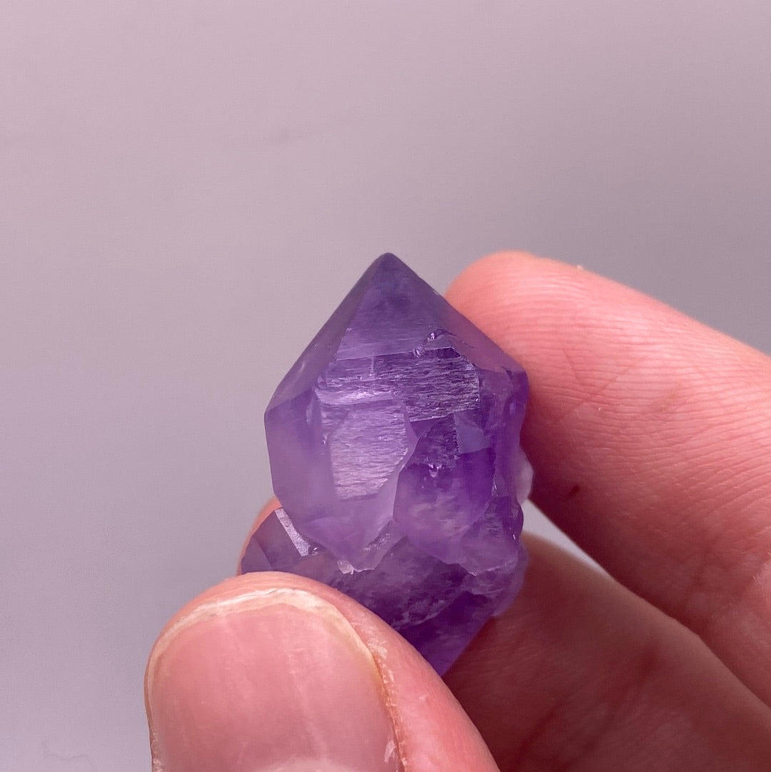 A collection of small amethyst clusters, each unique with 1-5 points, showcasing their natural beauty and vibrant purple hues.