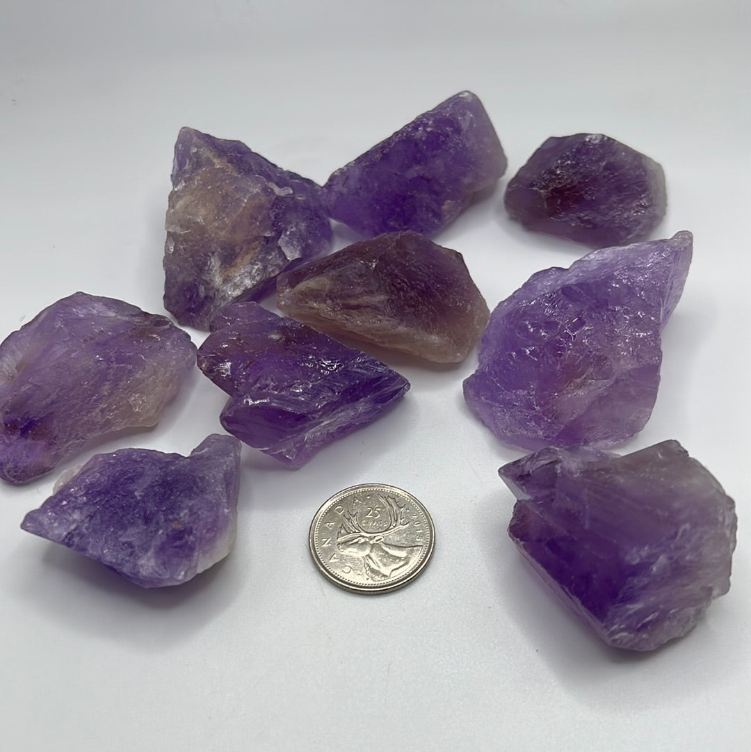 A collection of raw, unpolished amethyst gemstones showcasing their natural purple hues and unique textures, ideal for jewelry-making.