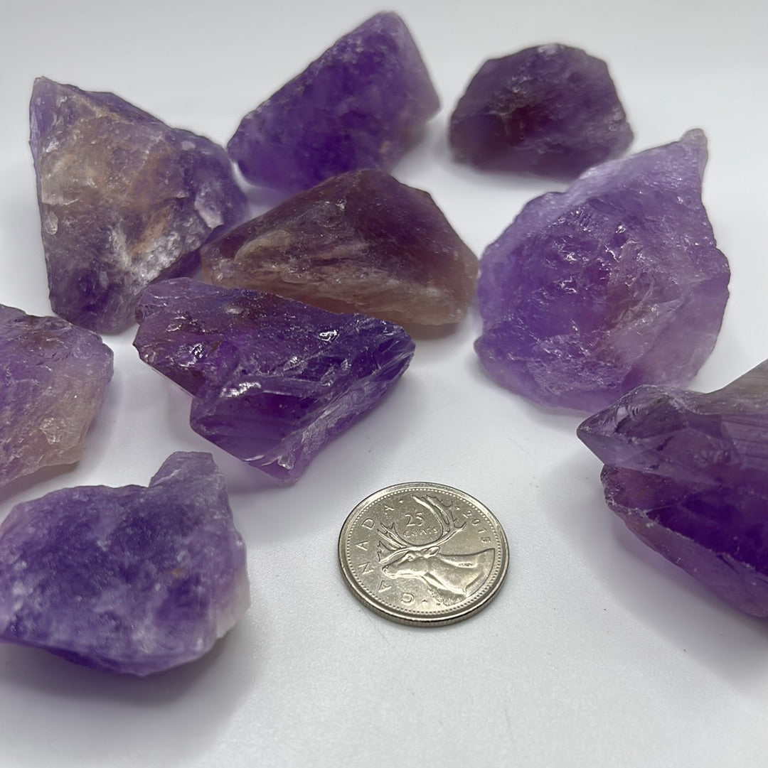 A collection of raw, unpolished amethyst gemstones showcasing their natural purple hues and unique textures, ideal for jewelry-making.