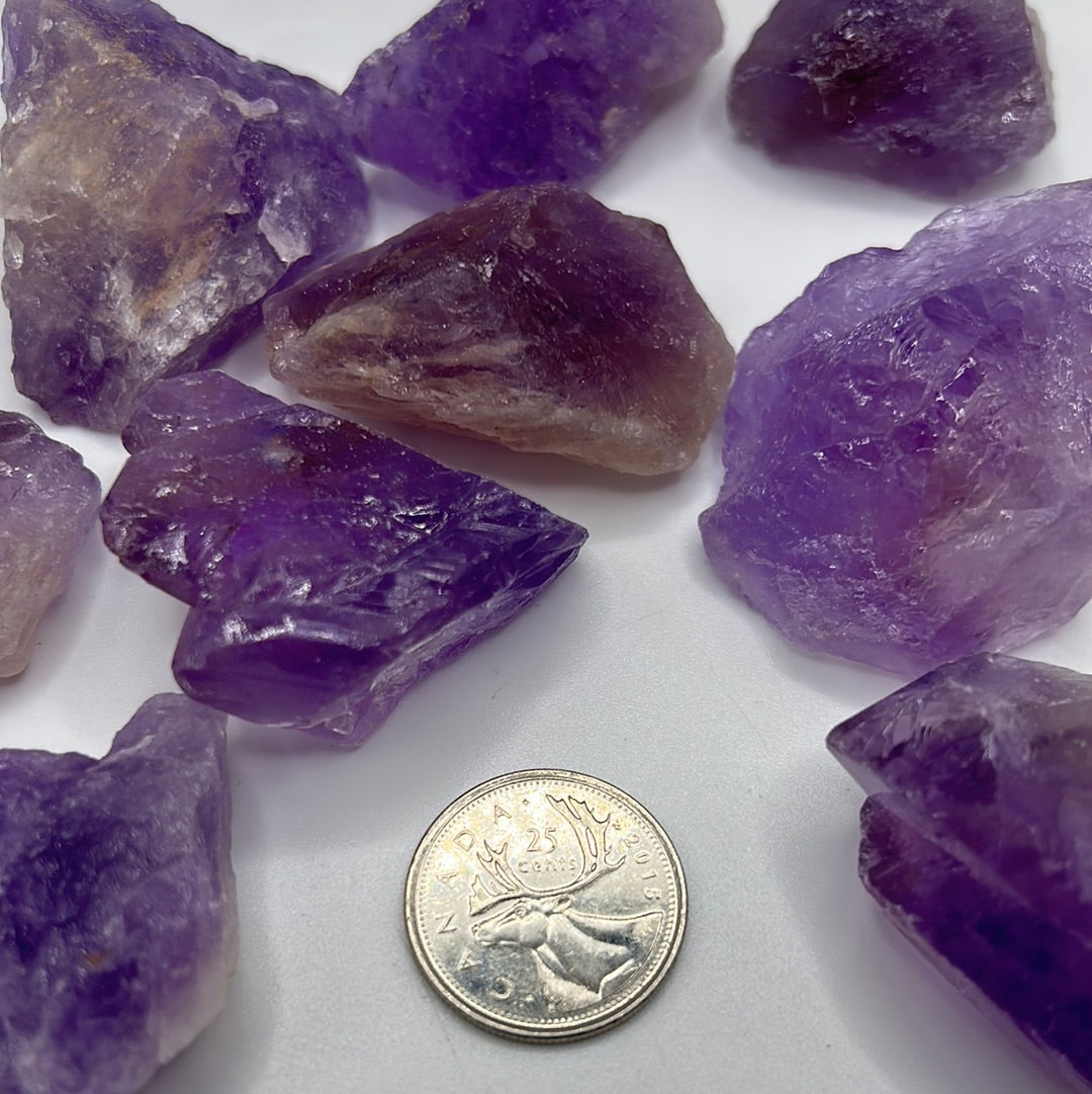 A collection of raw, unpolished amethyst gemstones showcasing their natural purple hues and unique textures, ideal for jewelry-making.