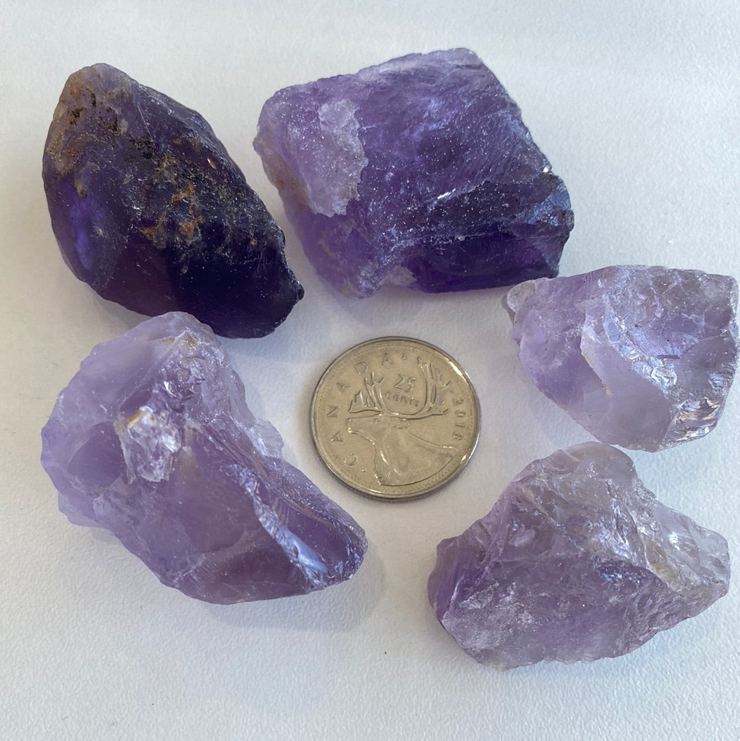 A collection of premium rough cut Amethyst stones, showcasing their natural purple hues and unique shapes, measuring approximately 1-2 inches.