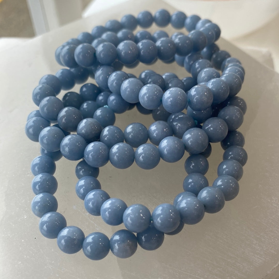 A close-up of an 8mm Angelite bracelet featuring pale blue beads, showcasing its handcrafted design and elastic band.