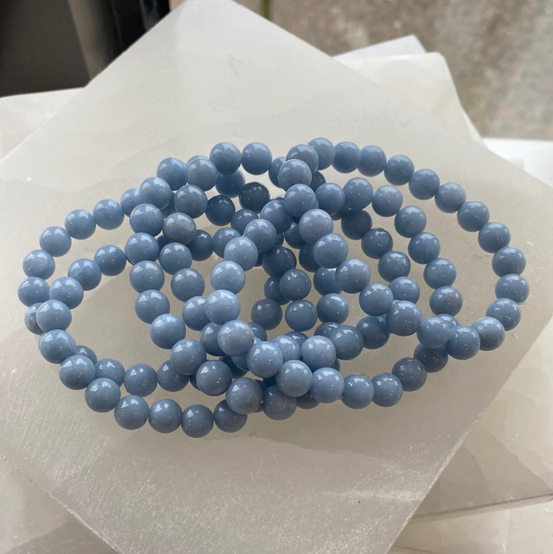 A close-up of an 8mm Angelite bracelet featuring pale blue beads, showcasing its handcrafted design and elastic band.