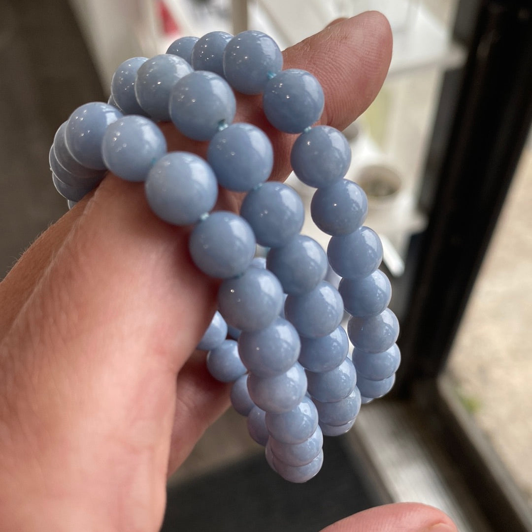 A close-up of an 8mm Angelite bracelet featuring pale blue beads, showcasing its handcrafted design and elastic band.