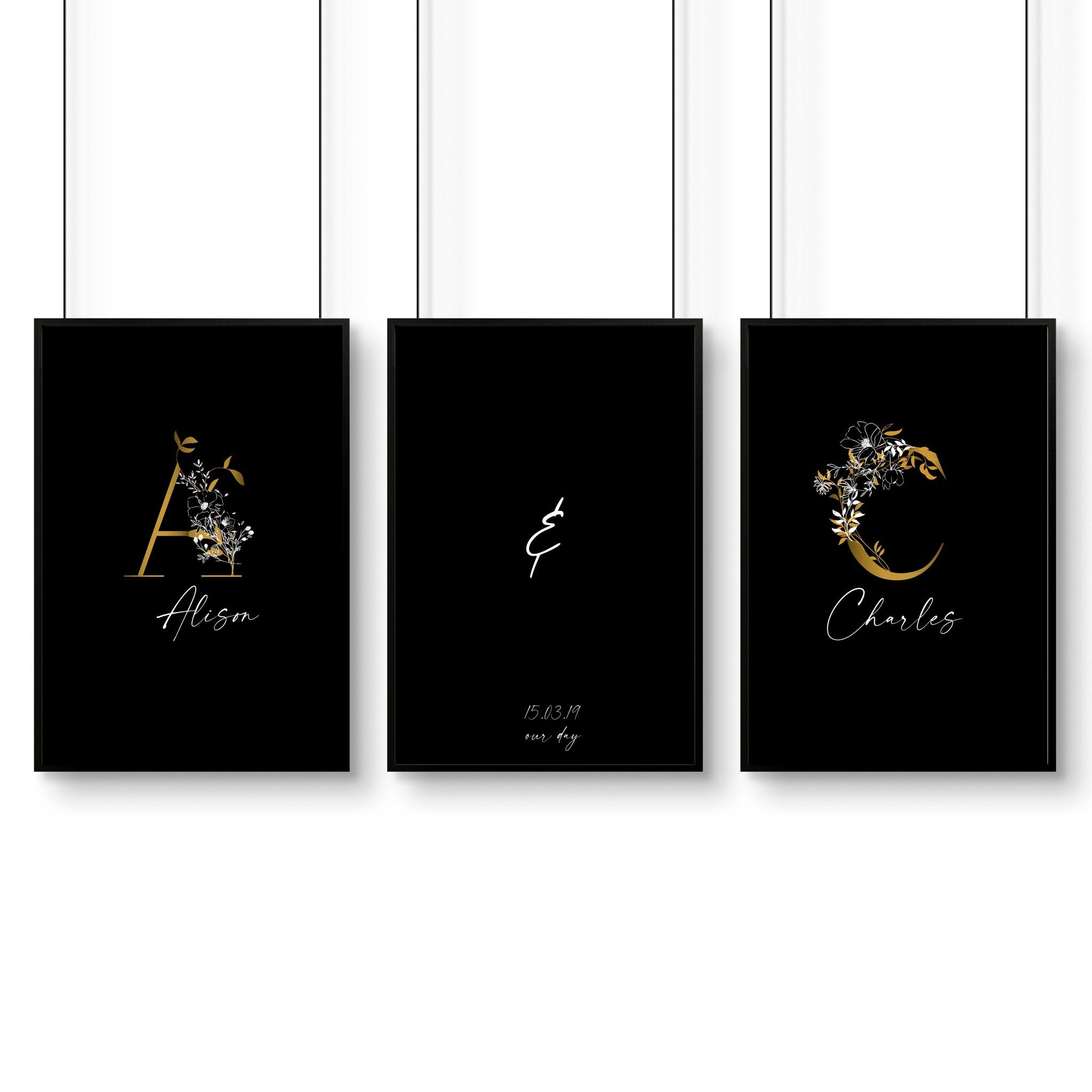 Set of 3 personalized wall art prints featuring botanical monogram designs in white, black, and gold on a black background.